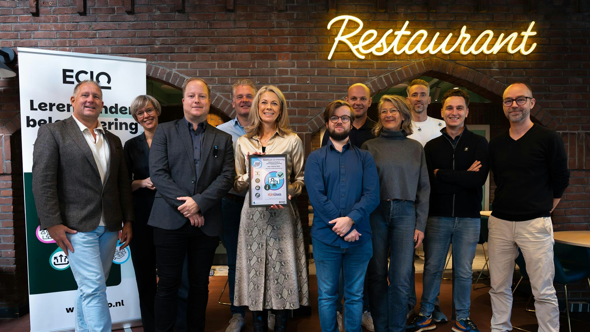 Groepsfoto met aan aantal personen. In het midden staat een vrouw met een certificaat in de hand