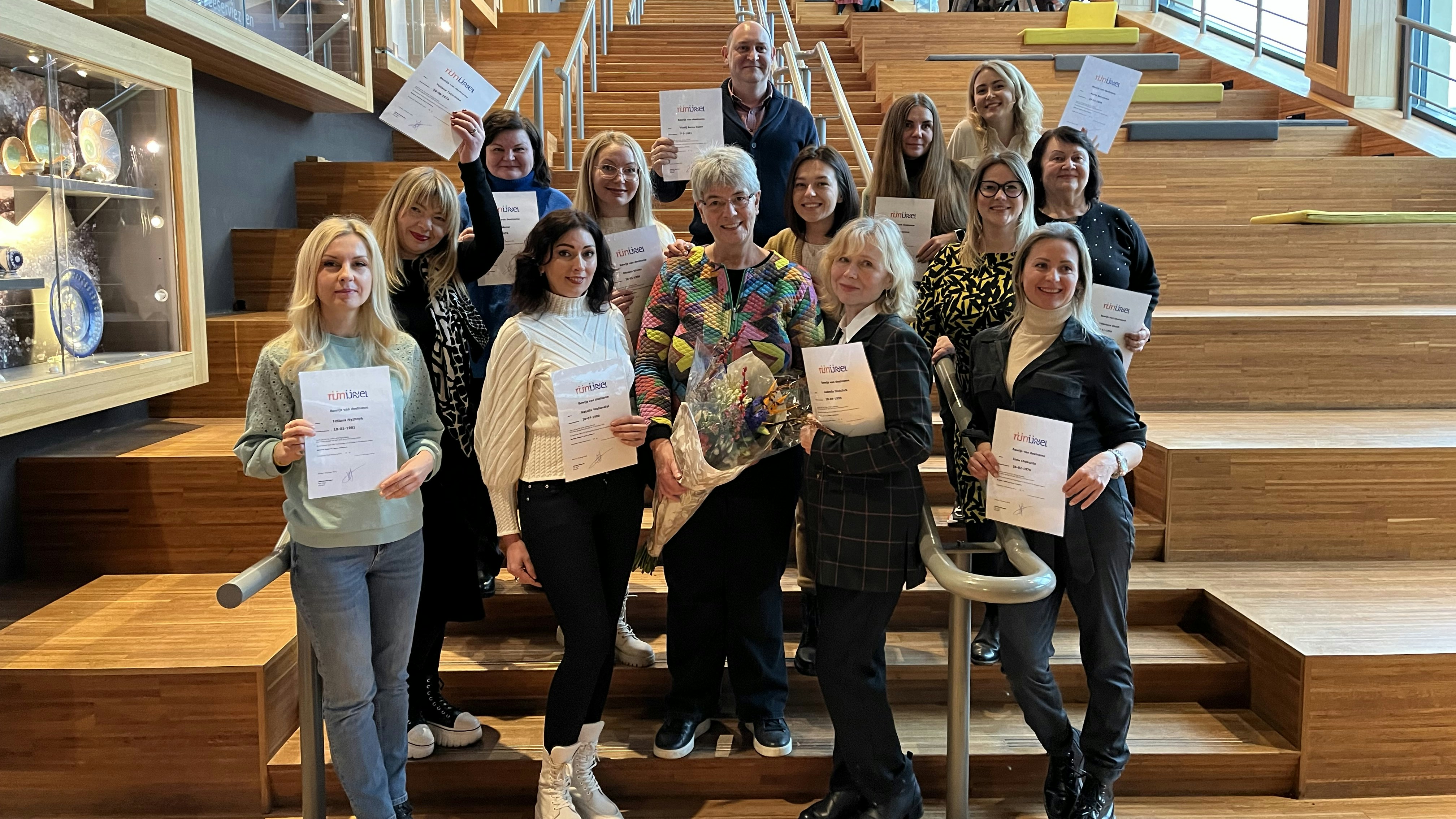 De groep Oekraïense vluchtelingen met hun taalcertificaat Nederlands. Met bloemen: docent Jolanda Sinnema