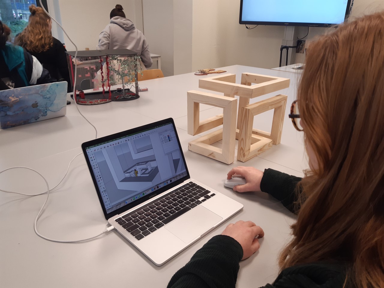 Student aan laptop met houten model