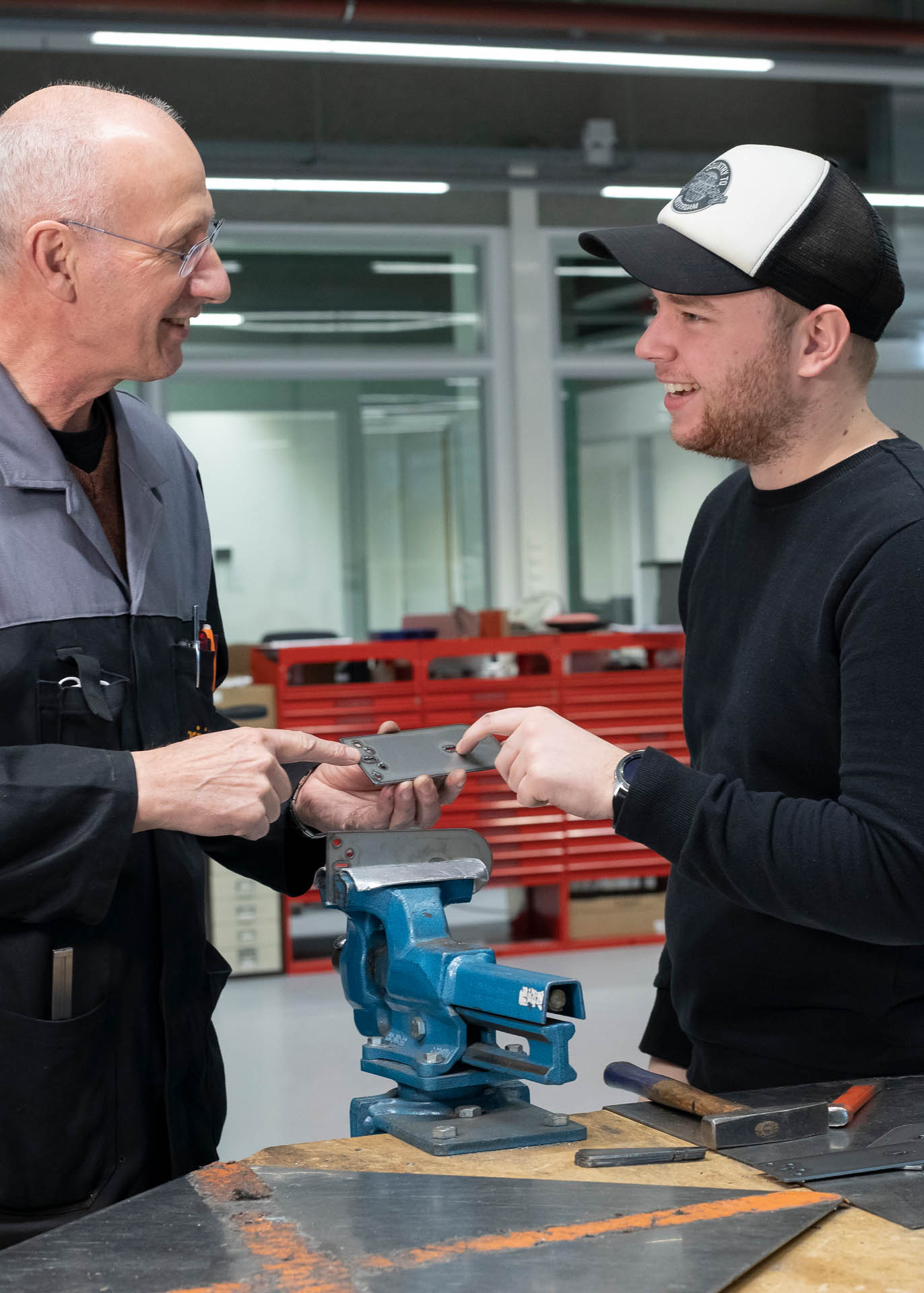 Student en docent overleggen en houden stuk metaal vast