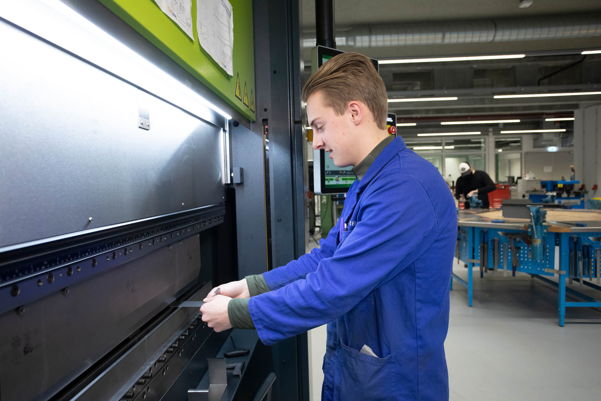 Student stop metaal in grote machine