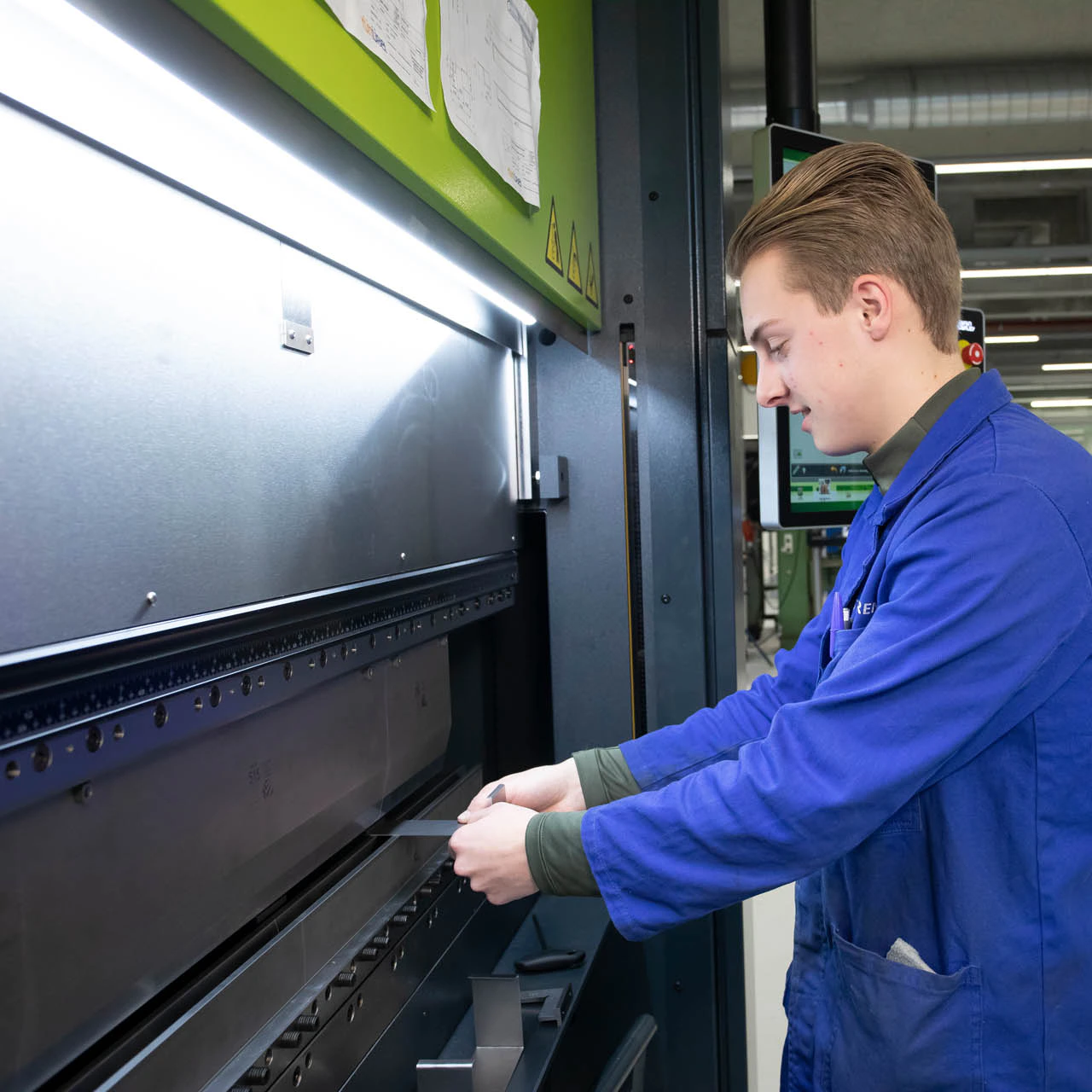 Student houdt stuk metaal vast bij machine