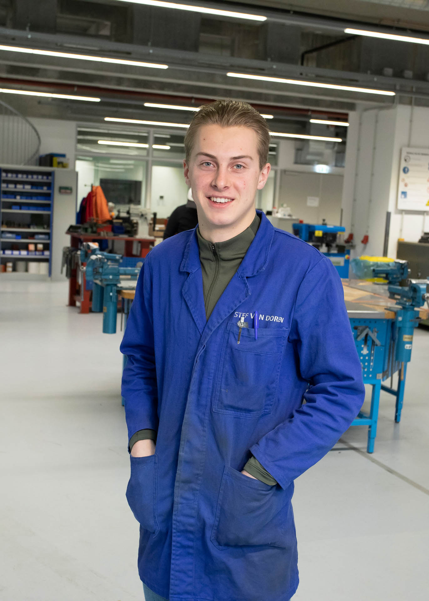 Student met werkkleding aan kijkt in camera