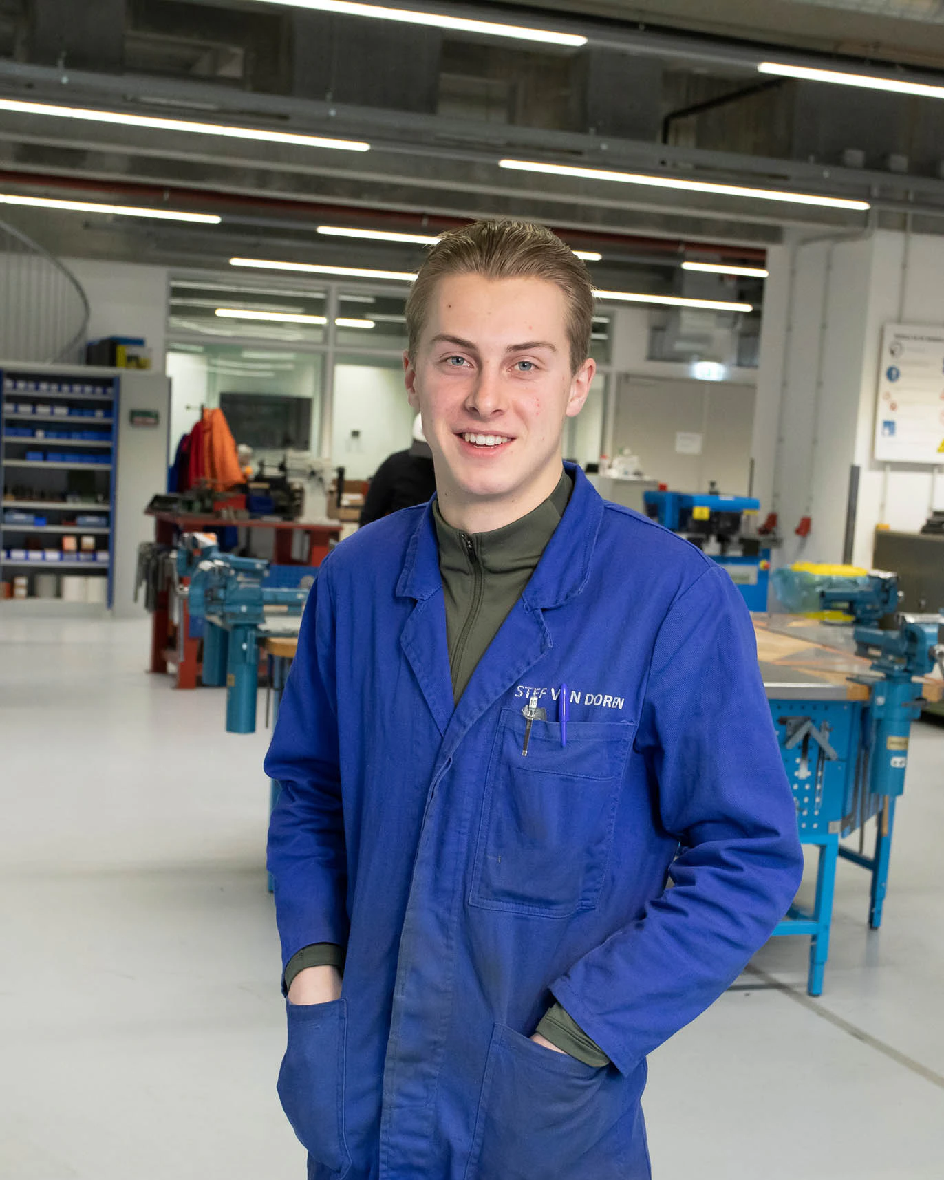 Student met werkkleding aan kijkt in camera