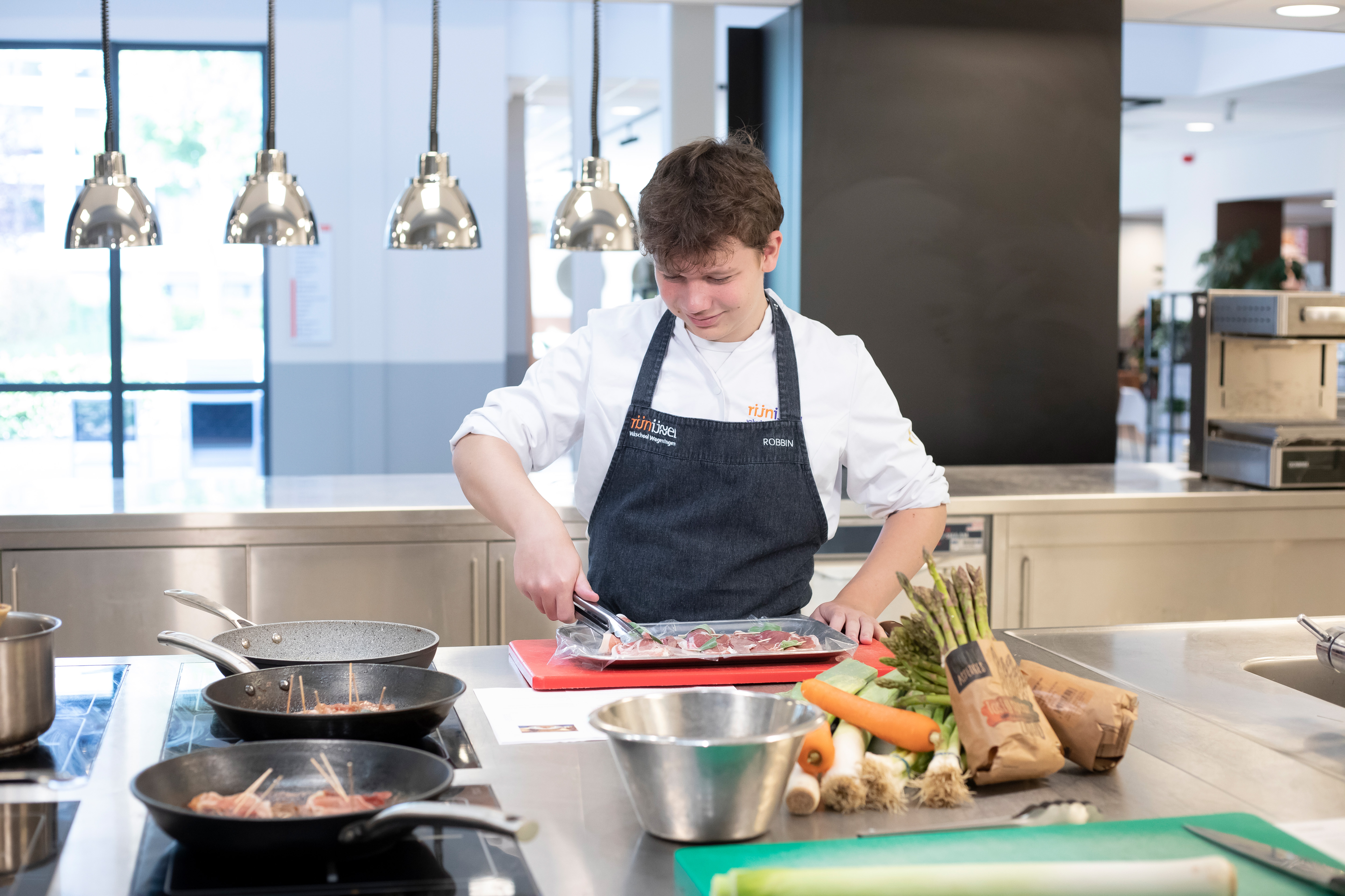 Jongen is aan het koken en heeft een tang in zijn hand