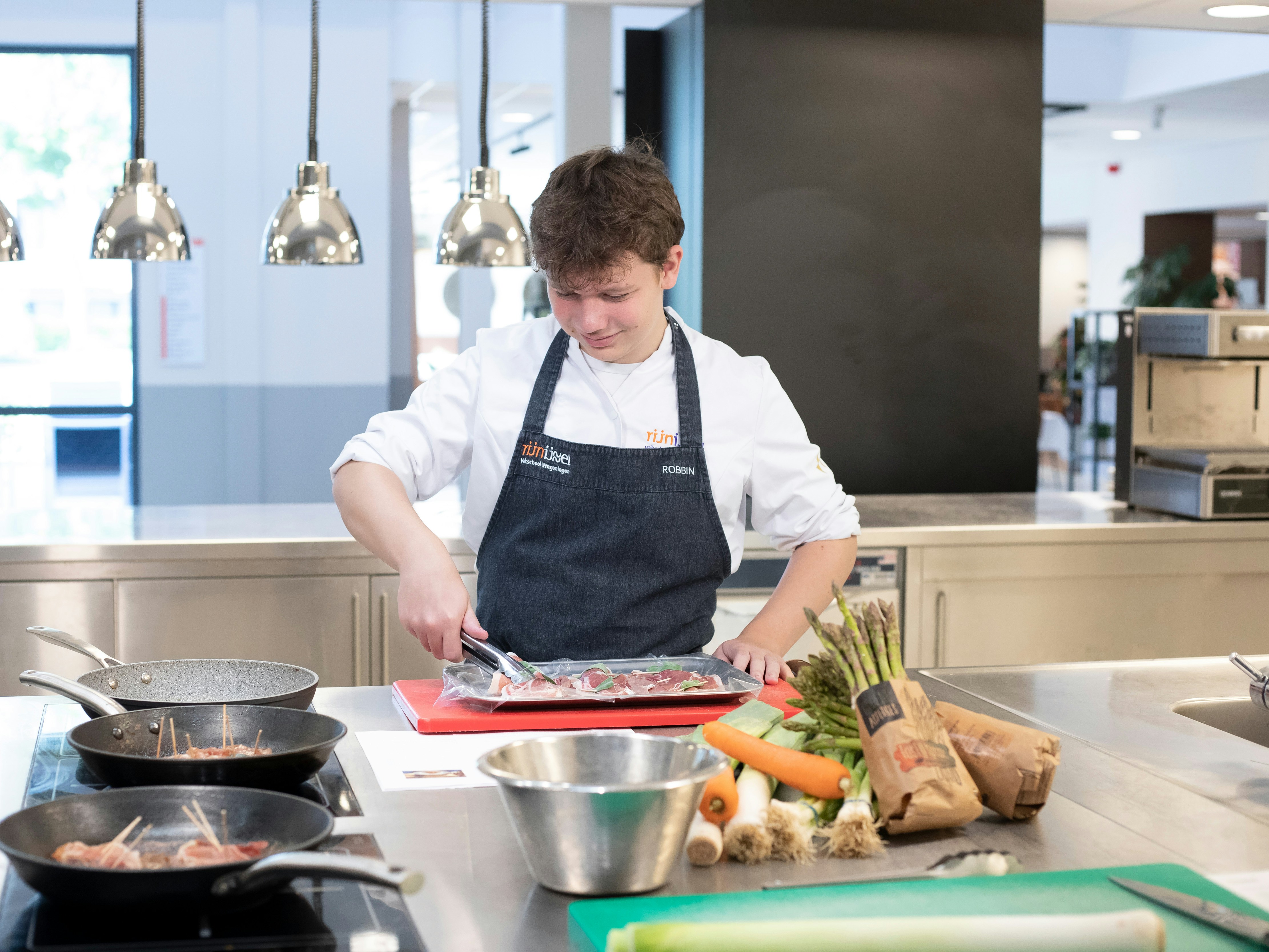 Jongen is aan het koken en heeft een tang in zijn hand