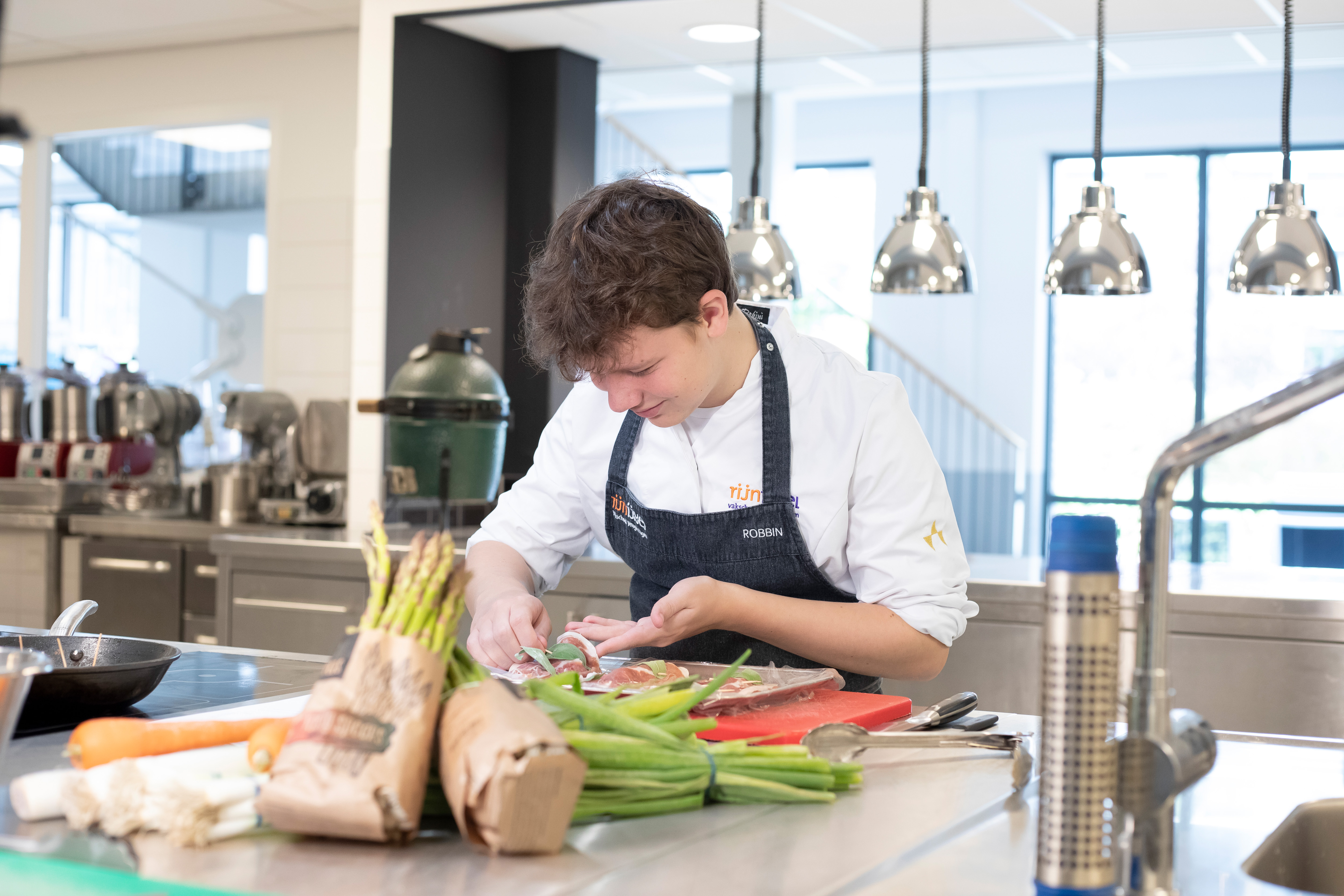 Jongen in kokskleding is aan een schaal eten aan het opmaken