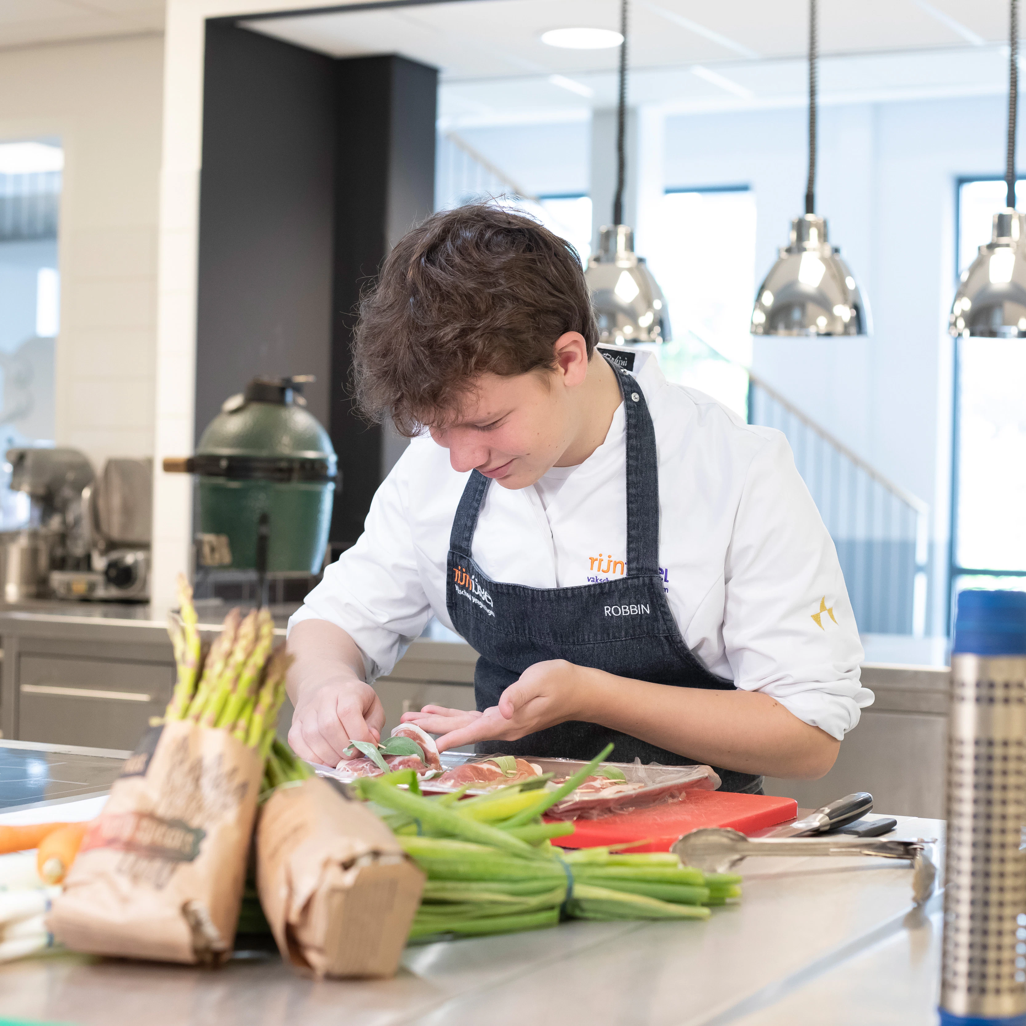 Jongen in kokskleding is aan een schaal eten aan het opmaken