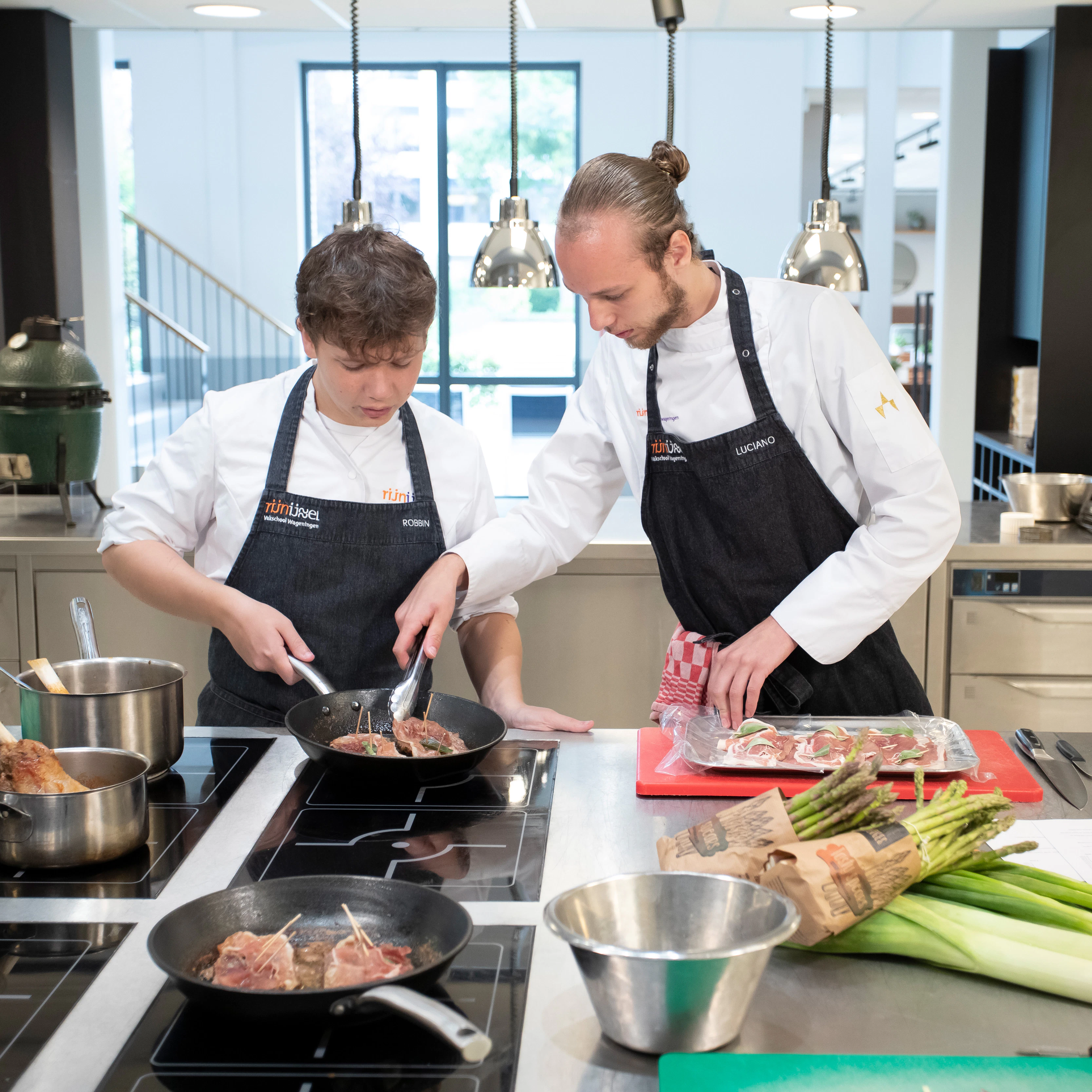 Twee jongens zijn aan het koken. Een van de jongens laat de andere zien hoe je moet koken