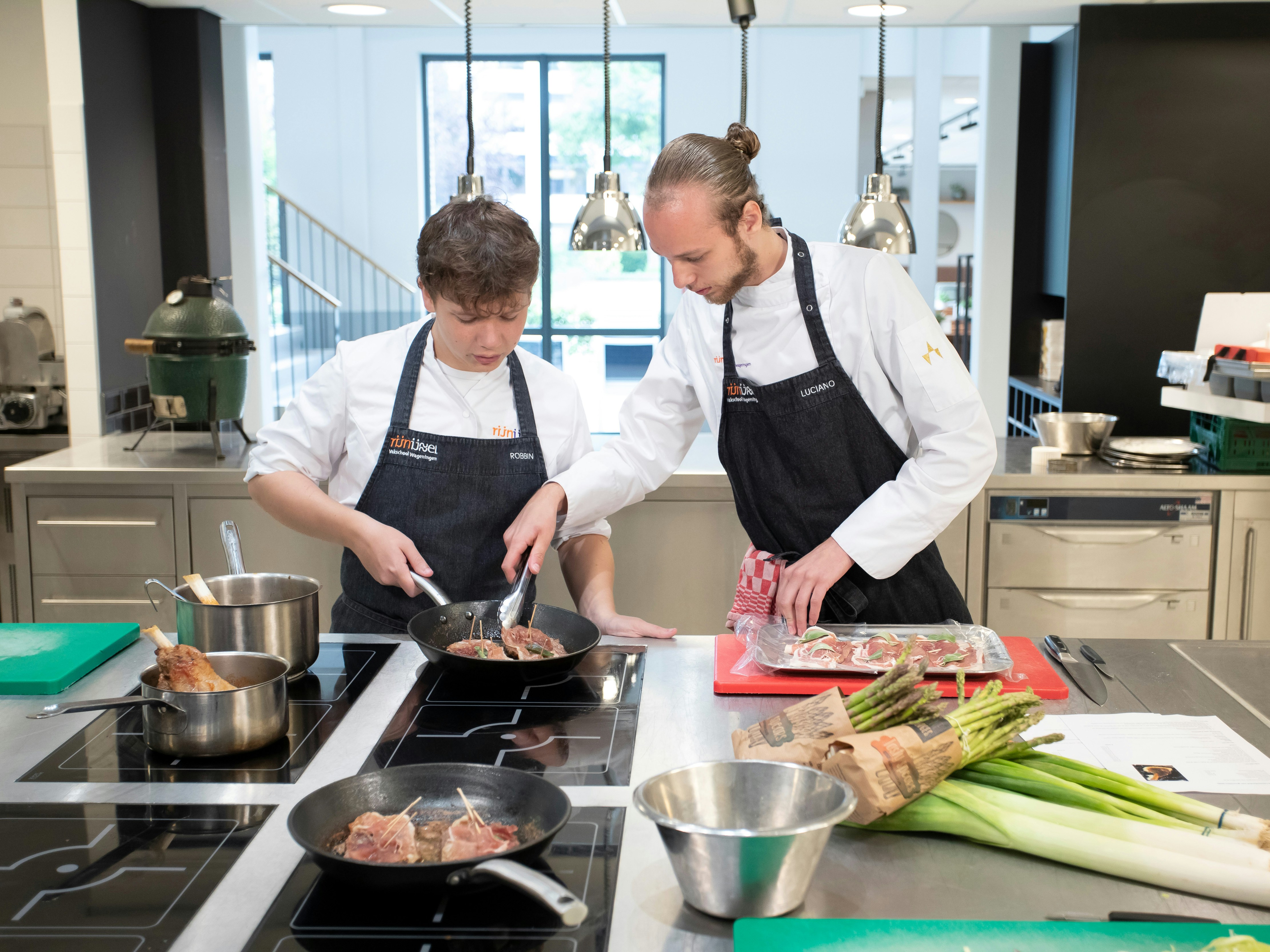 Twee jongens zijn aan het koken. Een van de jongens laat de andere zien hoe je moet koken