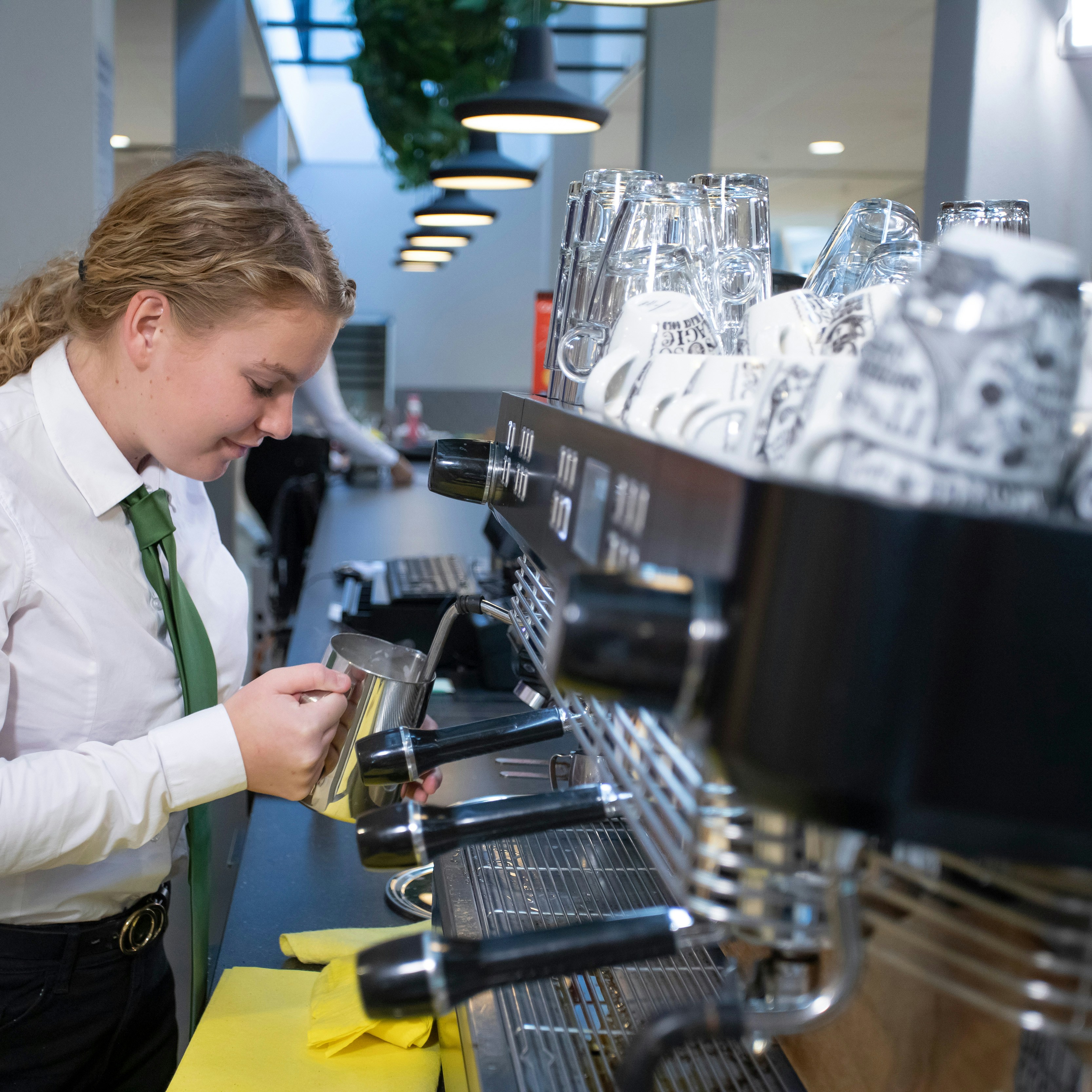 Meisje is melk aan het opschuimen voor de koffie