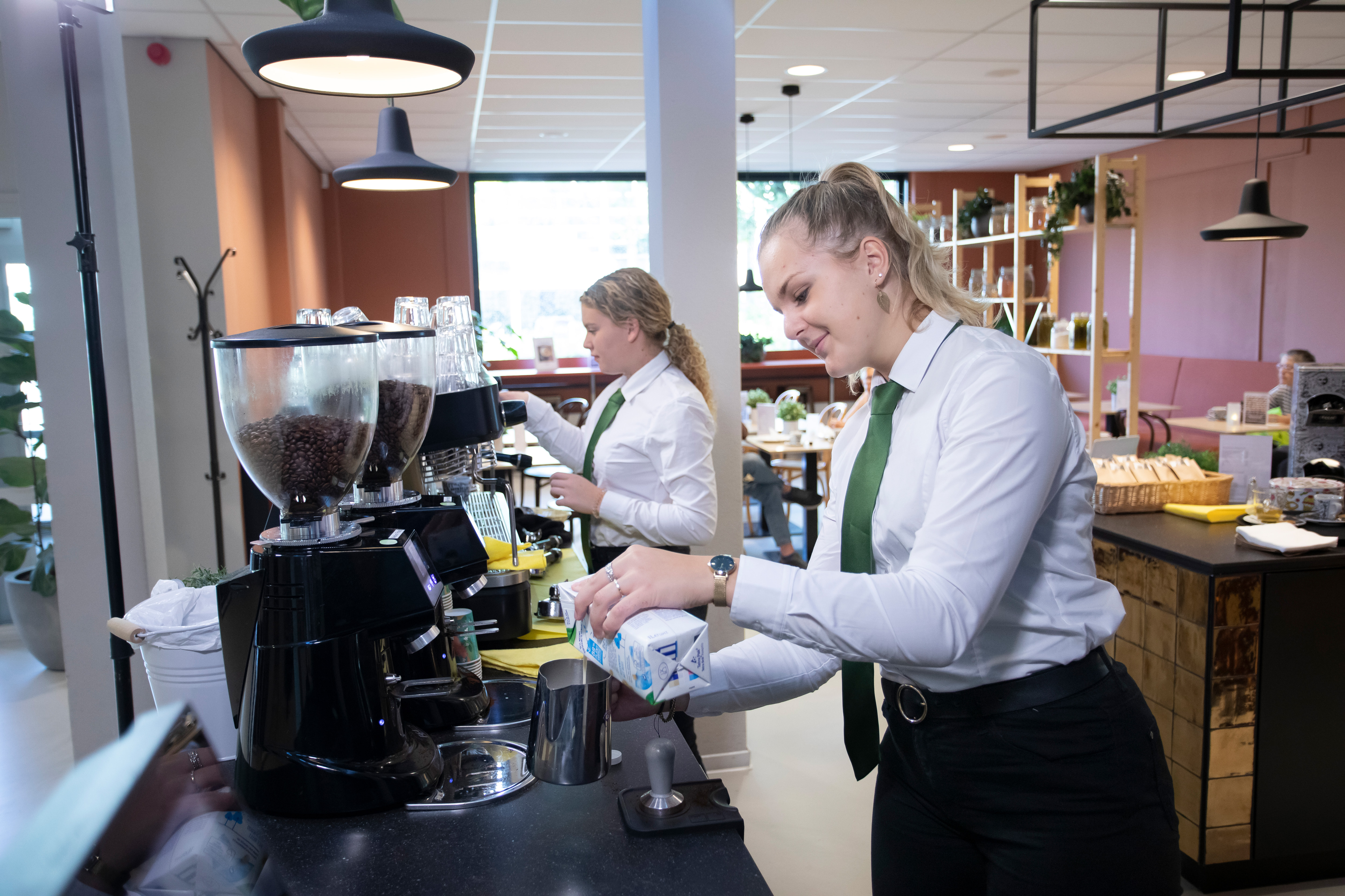 Meisje doet melk in de schuimer voor de cappucino