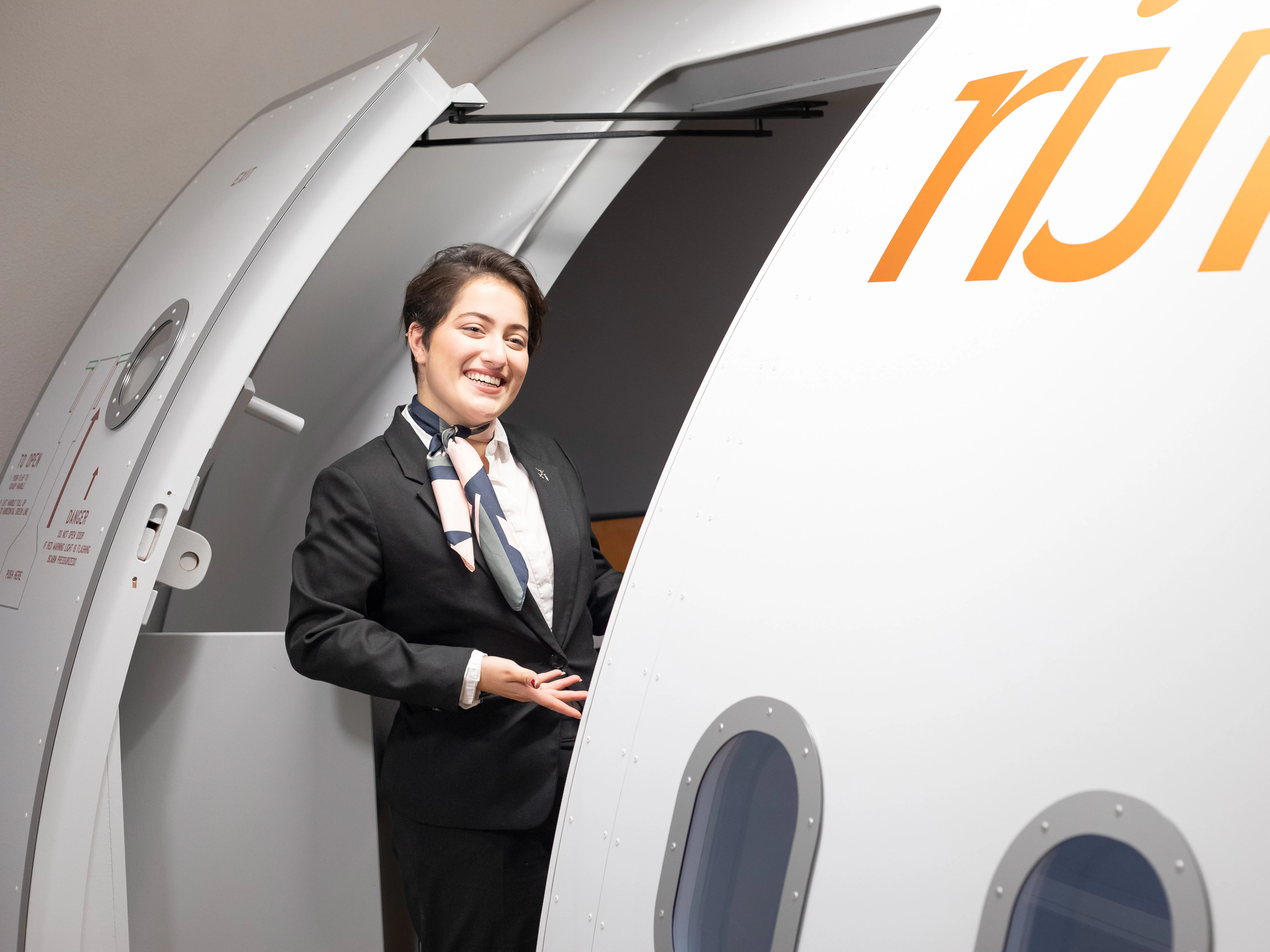 Student staat bij de ingang van een vliegtuig en wijst de weg naar binnen