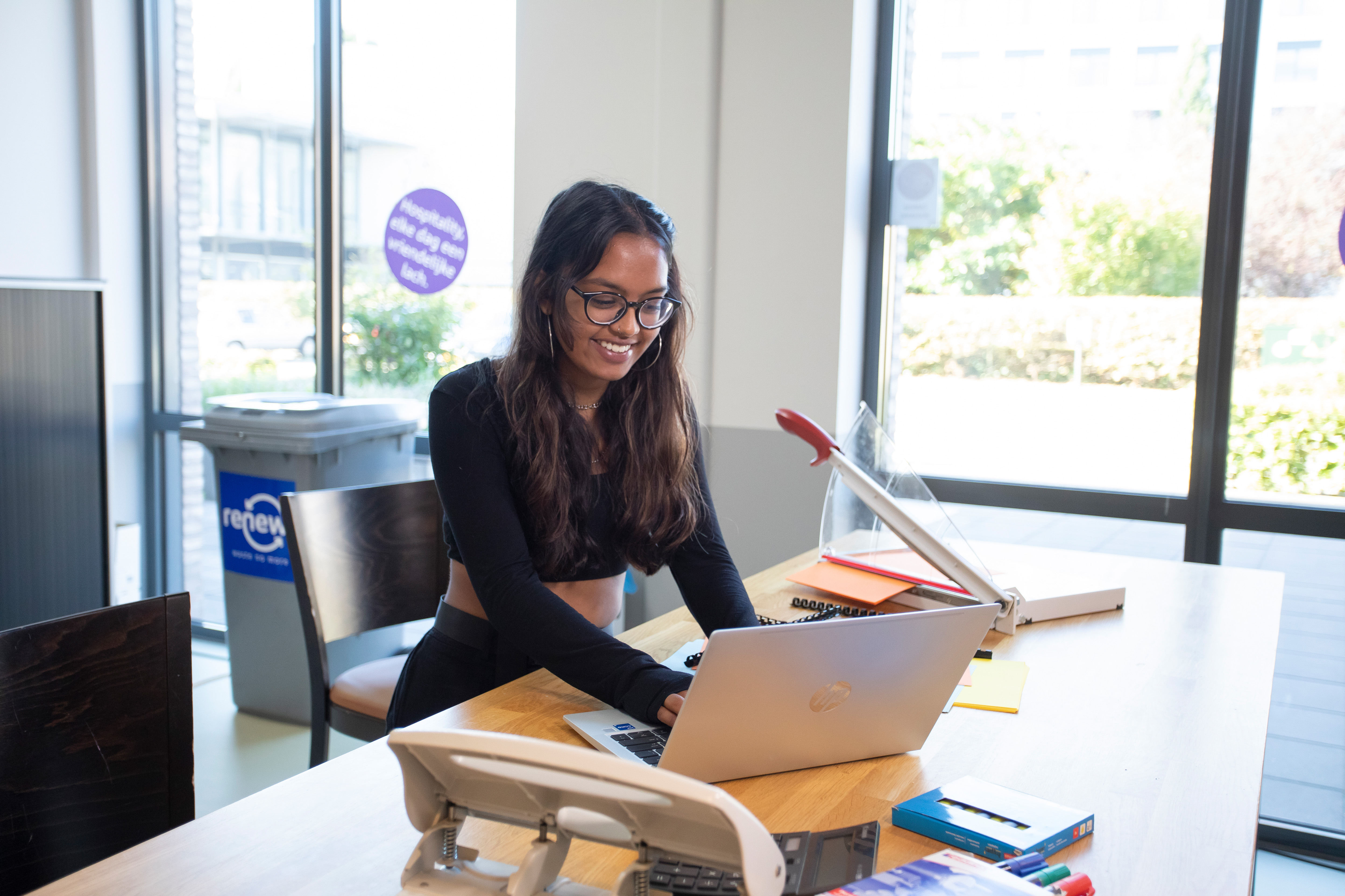 Een meisje zit achter de laptop. Ze kijkt naar het beeldscherm