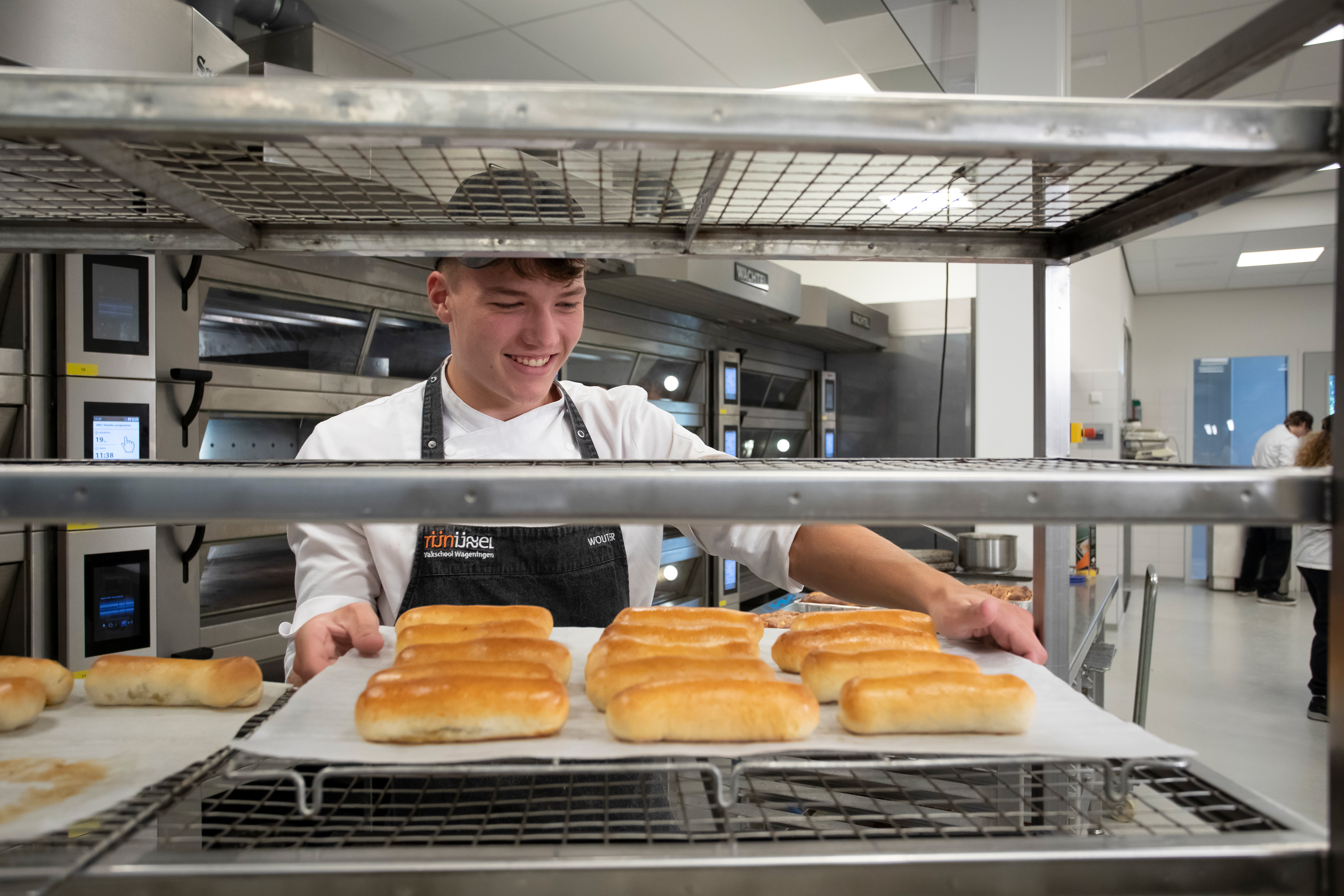 Student haalt een schaal met brood van een kar af