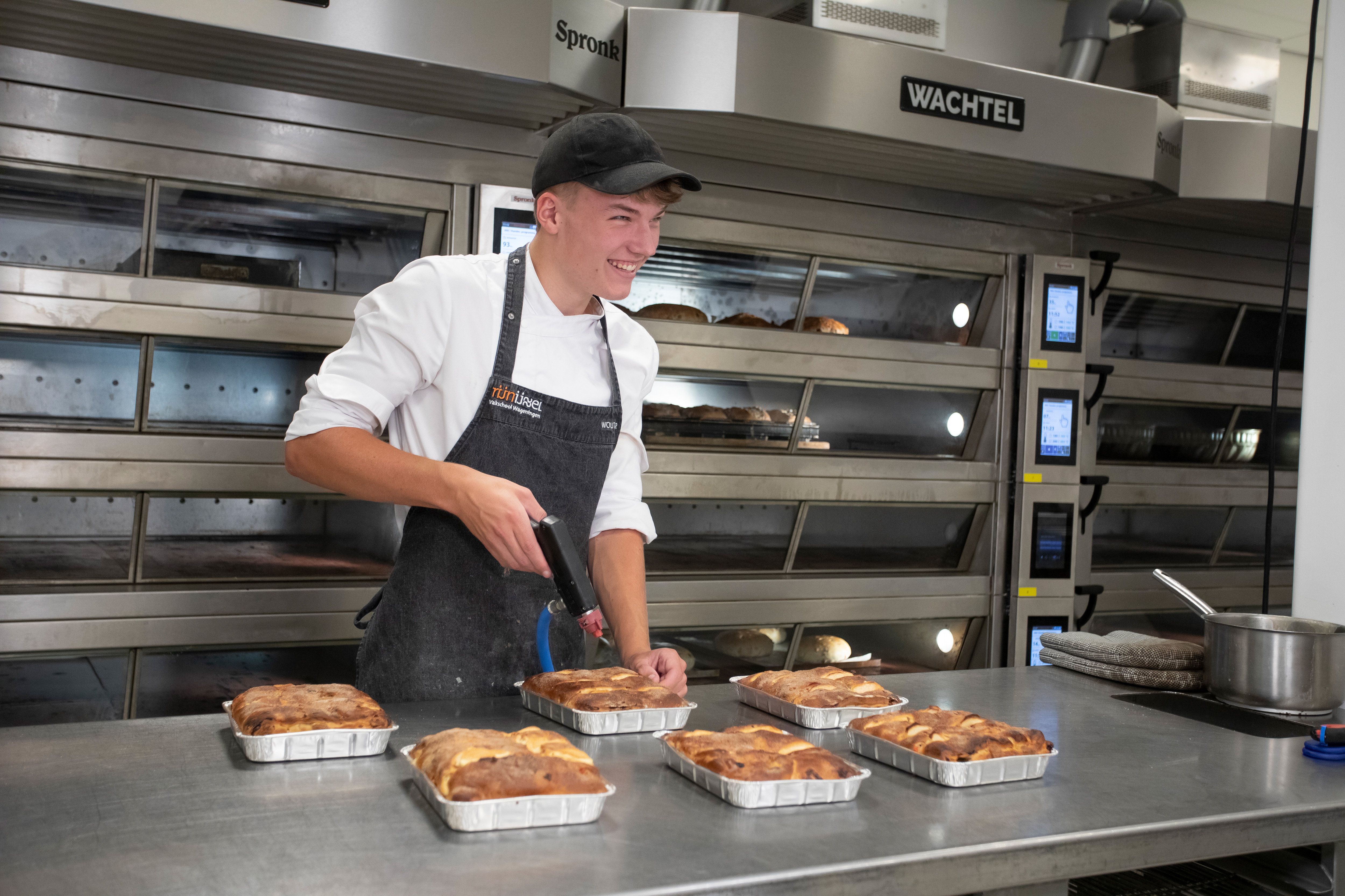 Student in bakkerskleding is bezig met het bewerken van brood