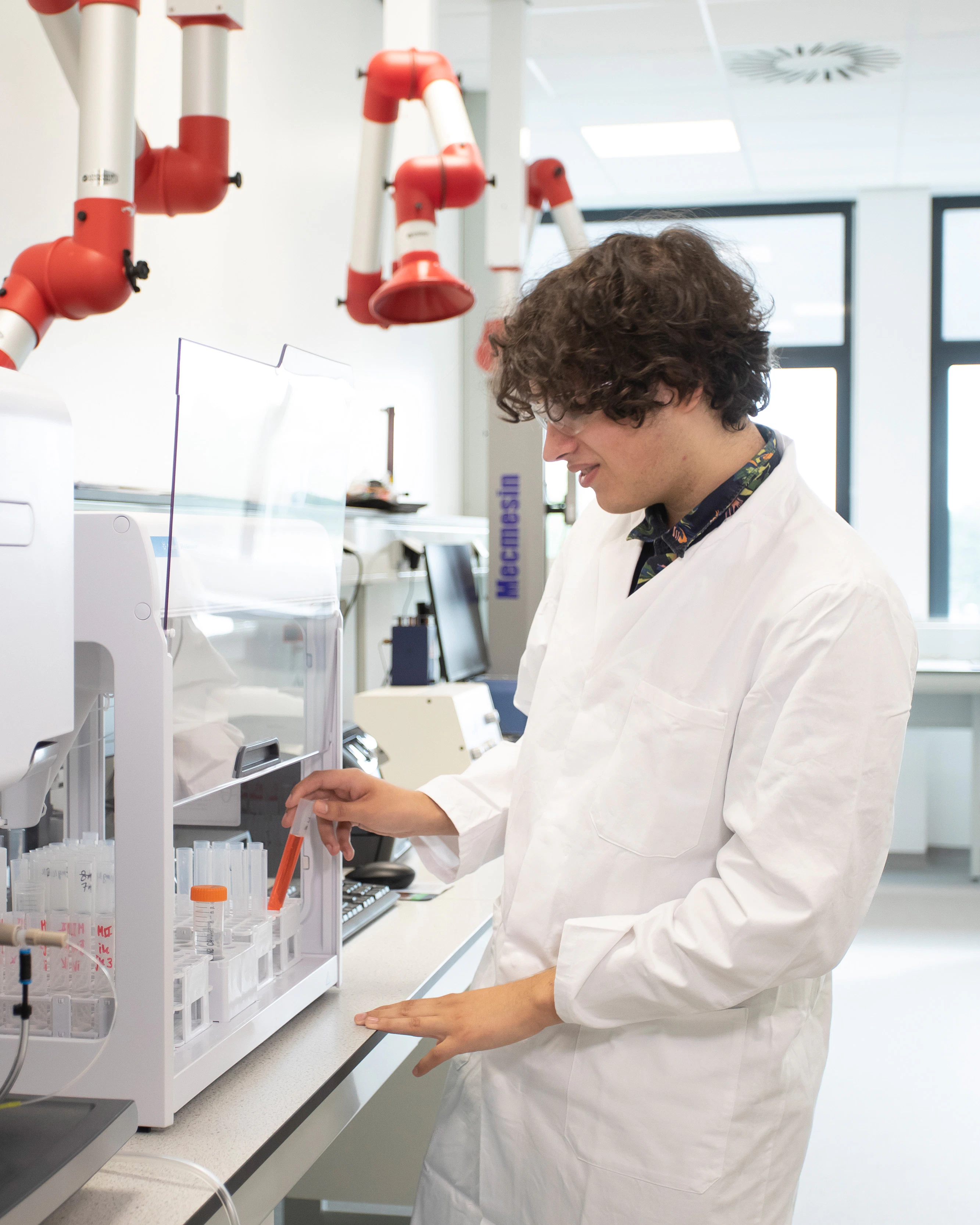 Jongen in een labaratoriumjas zit achter een microscoop