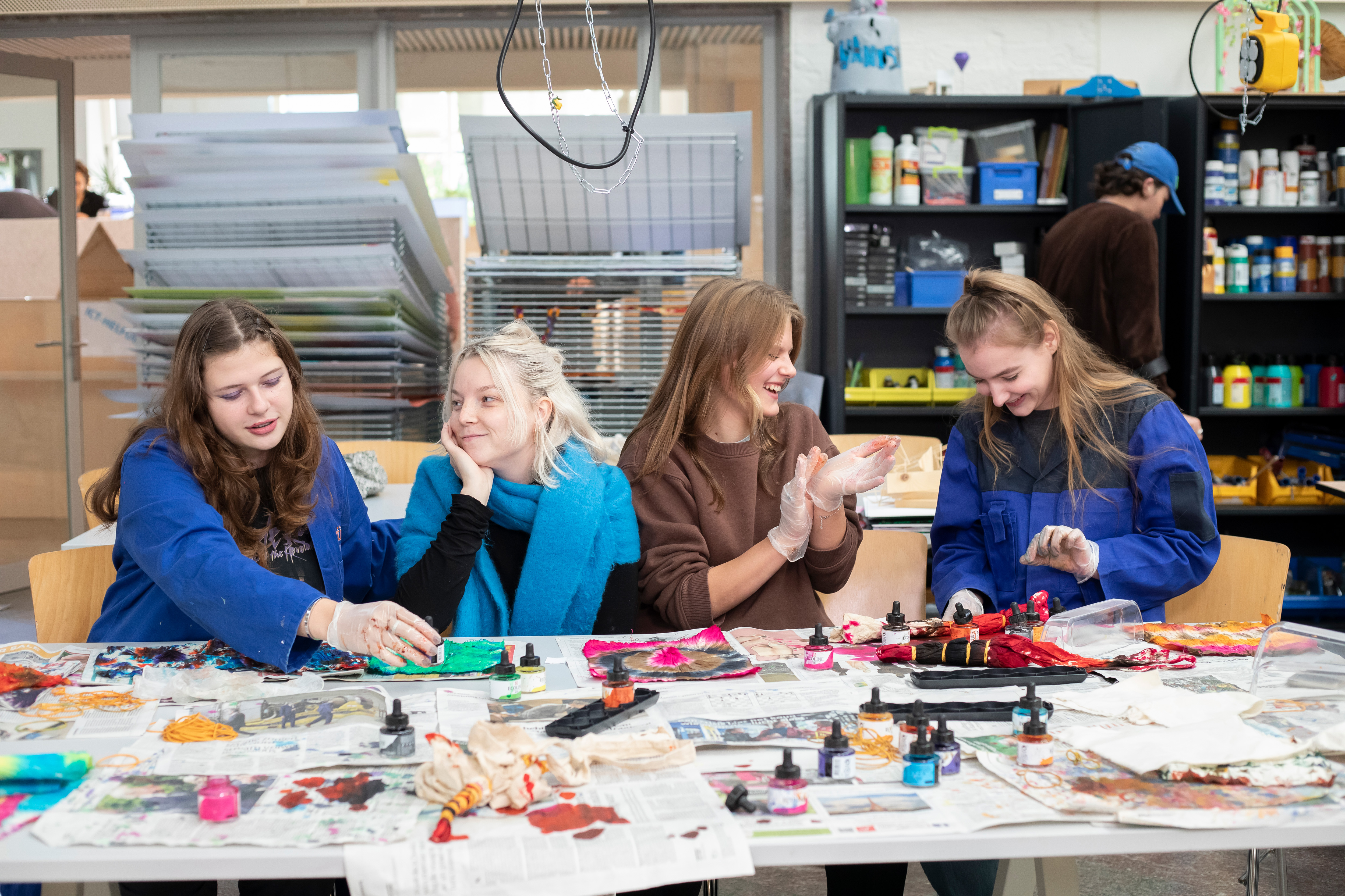 4 studenten zitten aan tafel terwijl ze aan het werk zijn en met elkaar praten
