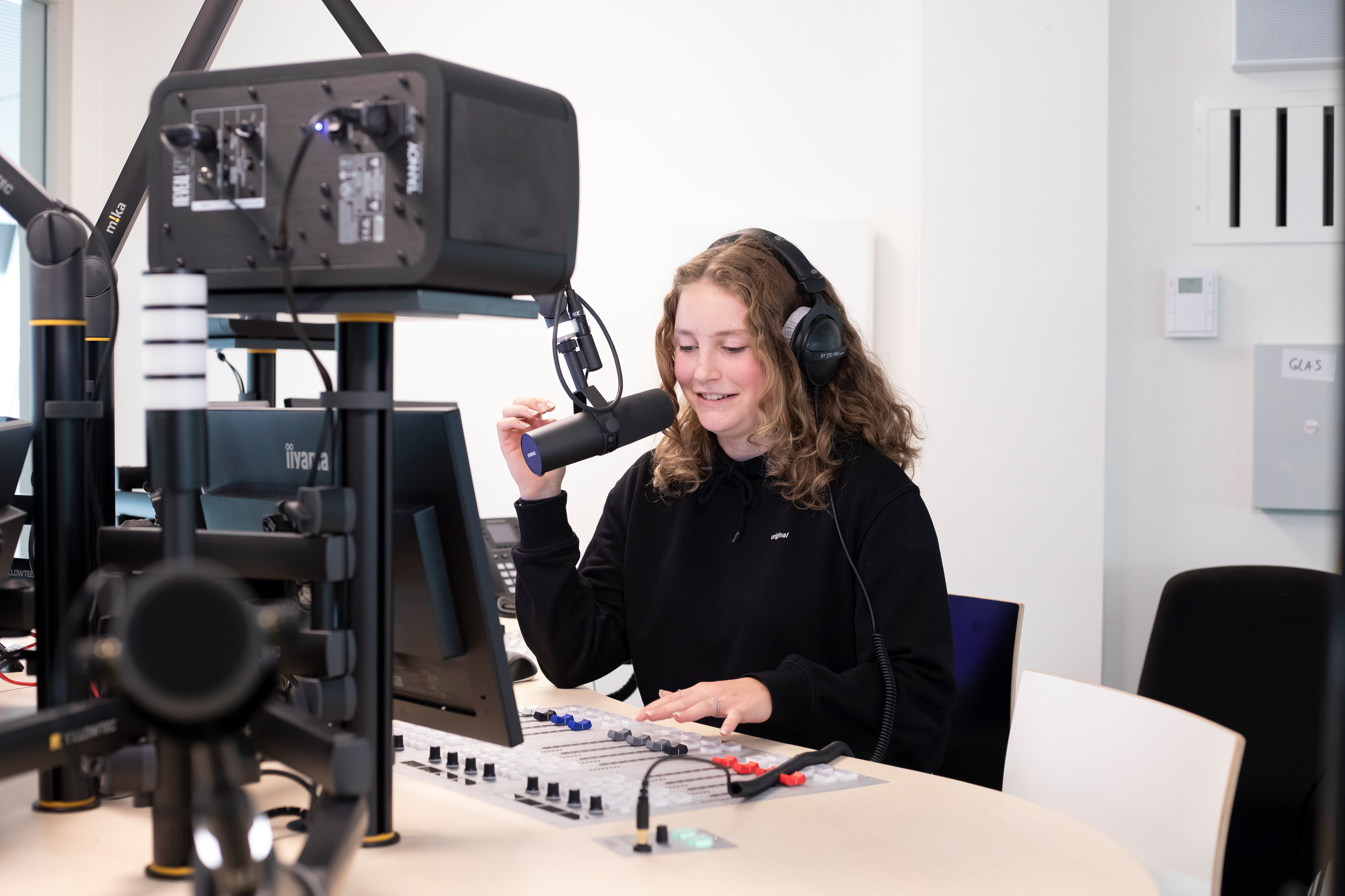 Student zit achter een microfoon met een koptelefoon op