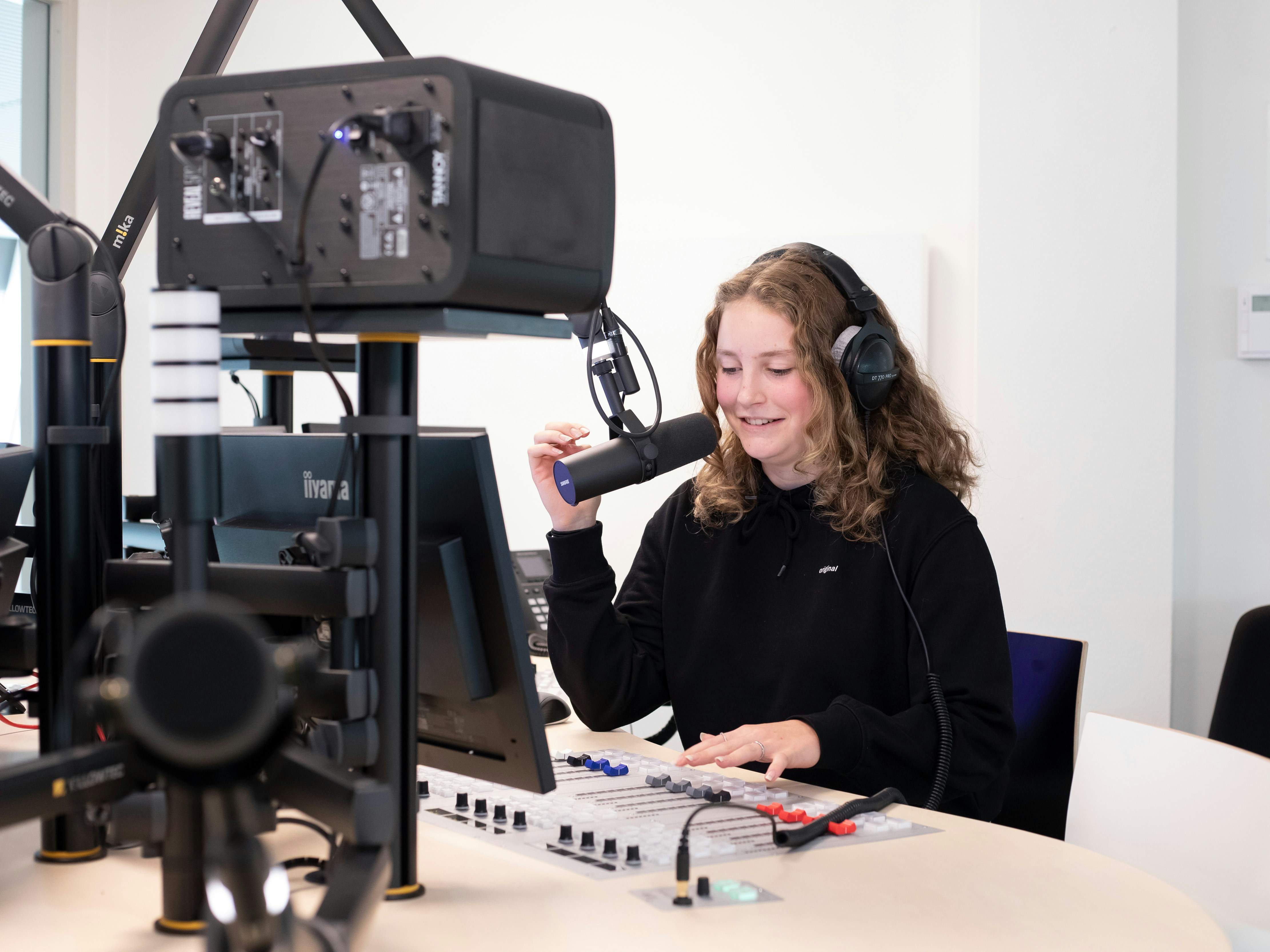 Student zit achter een microfoon met een koptelefoon op