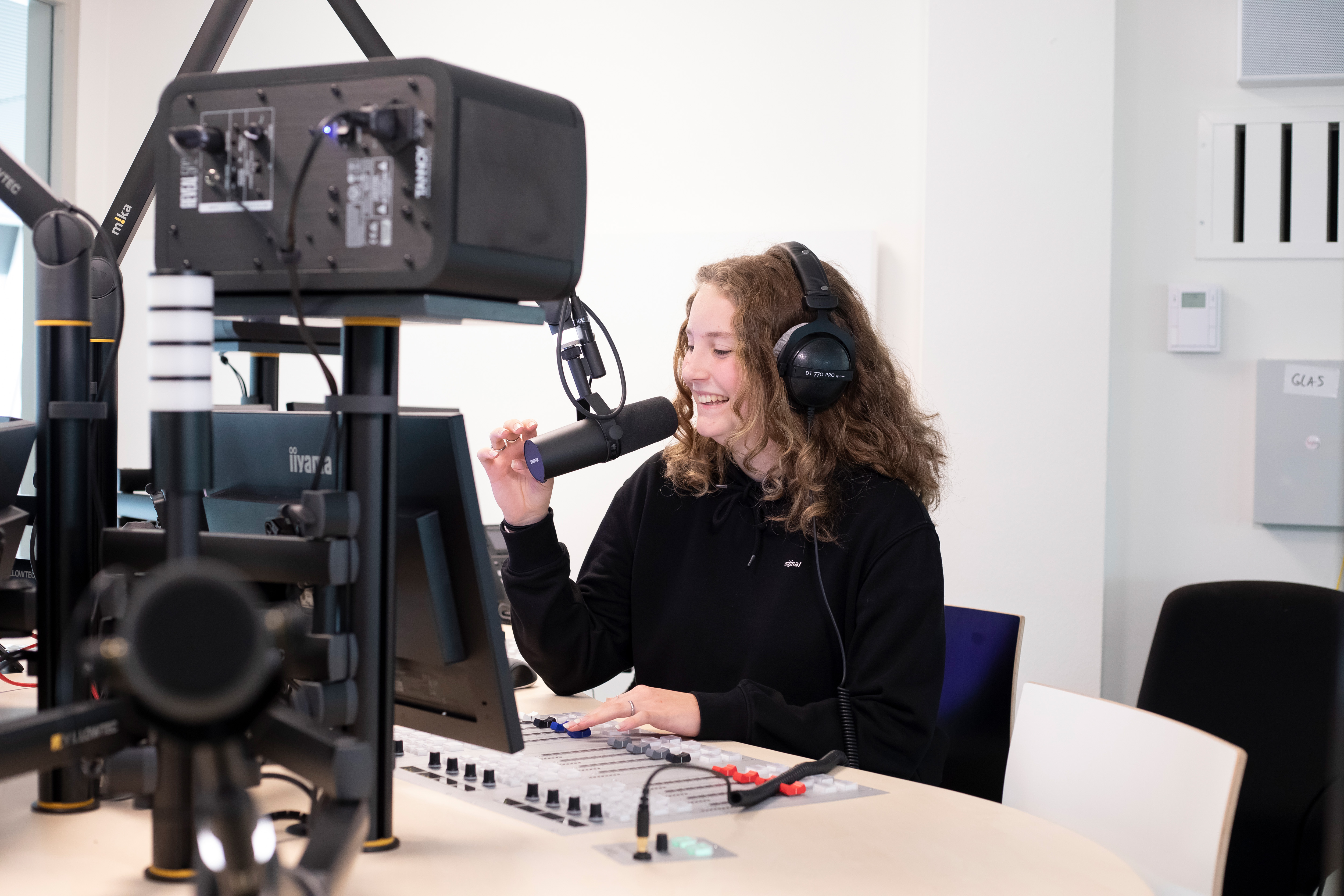 student zit in een radiostudio en praat door een microfoon