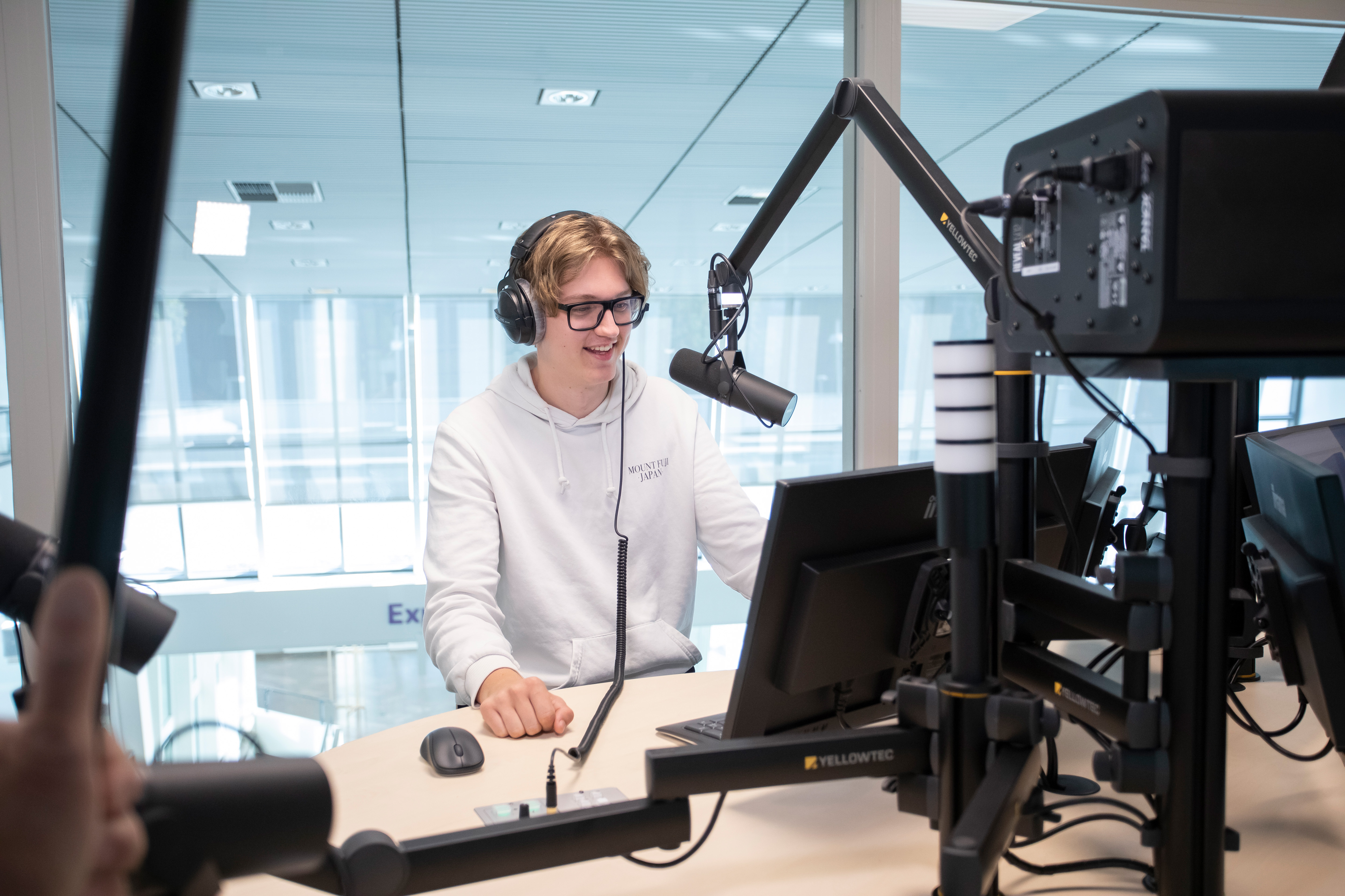 Student zit achter een microfoon met een koptelefoon op