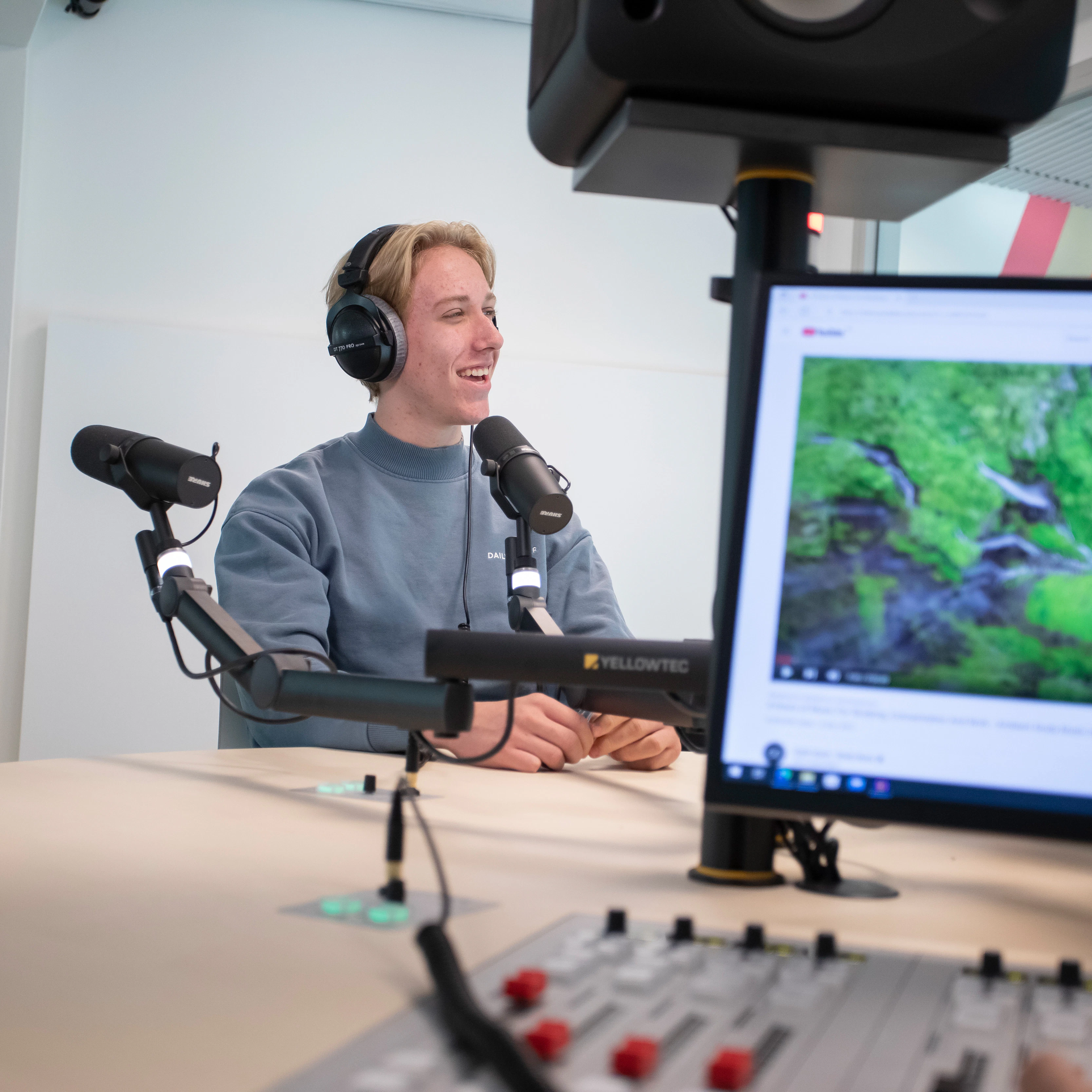 Student zit achter een microfoon met een koptelefoon op