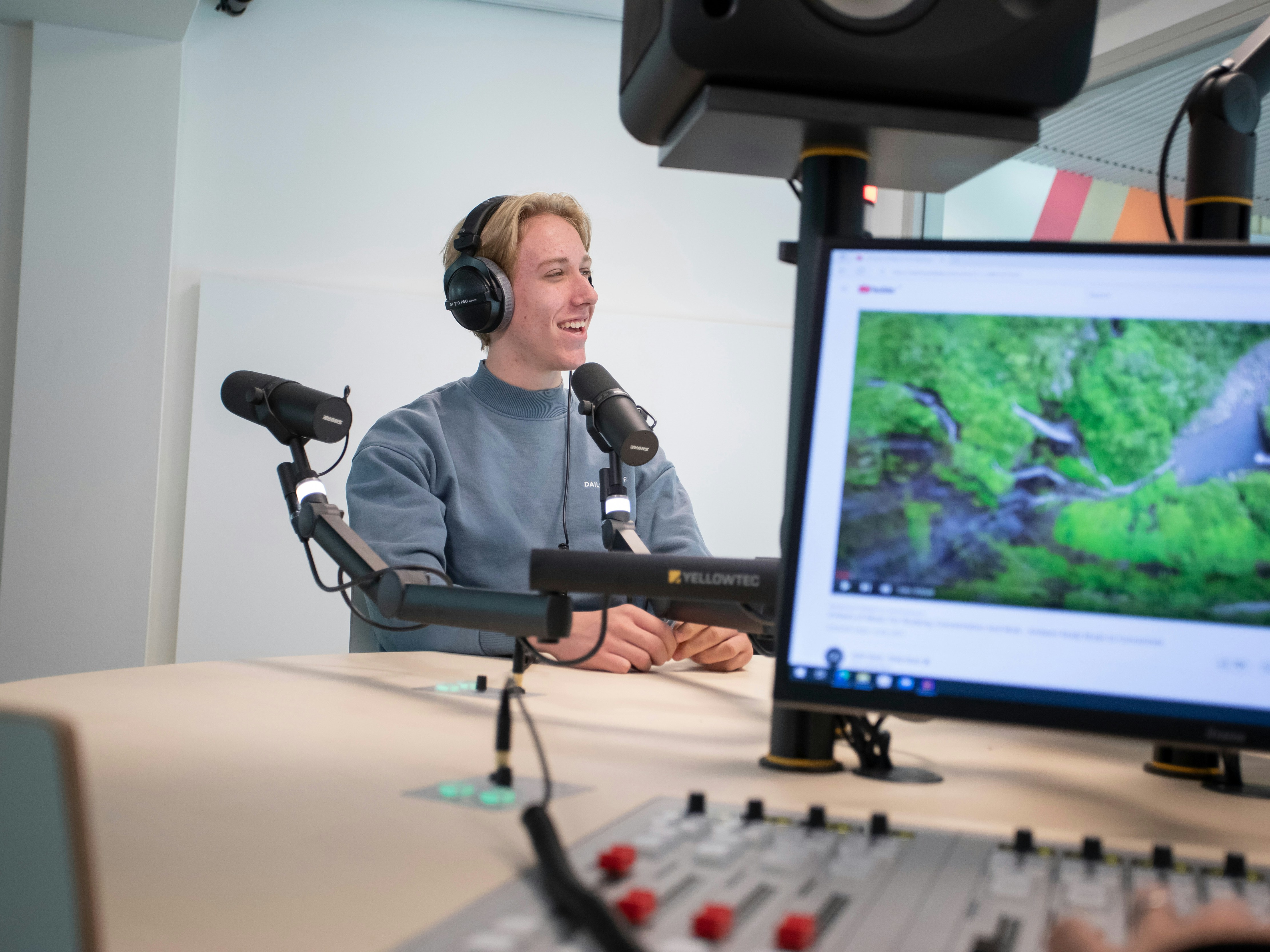 Student zit achter een microfoon met een koptelefoon op