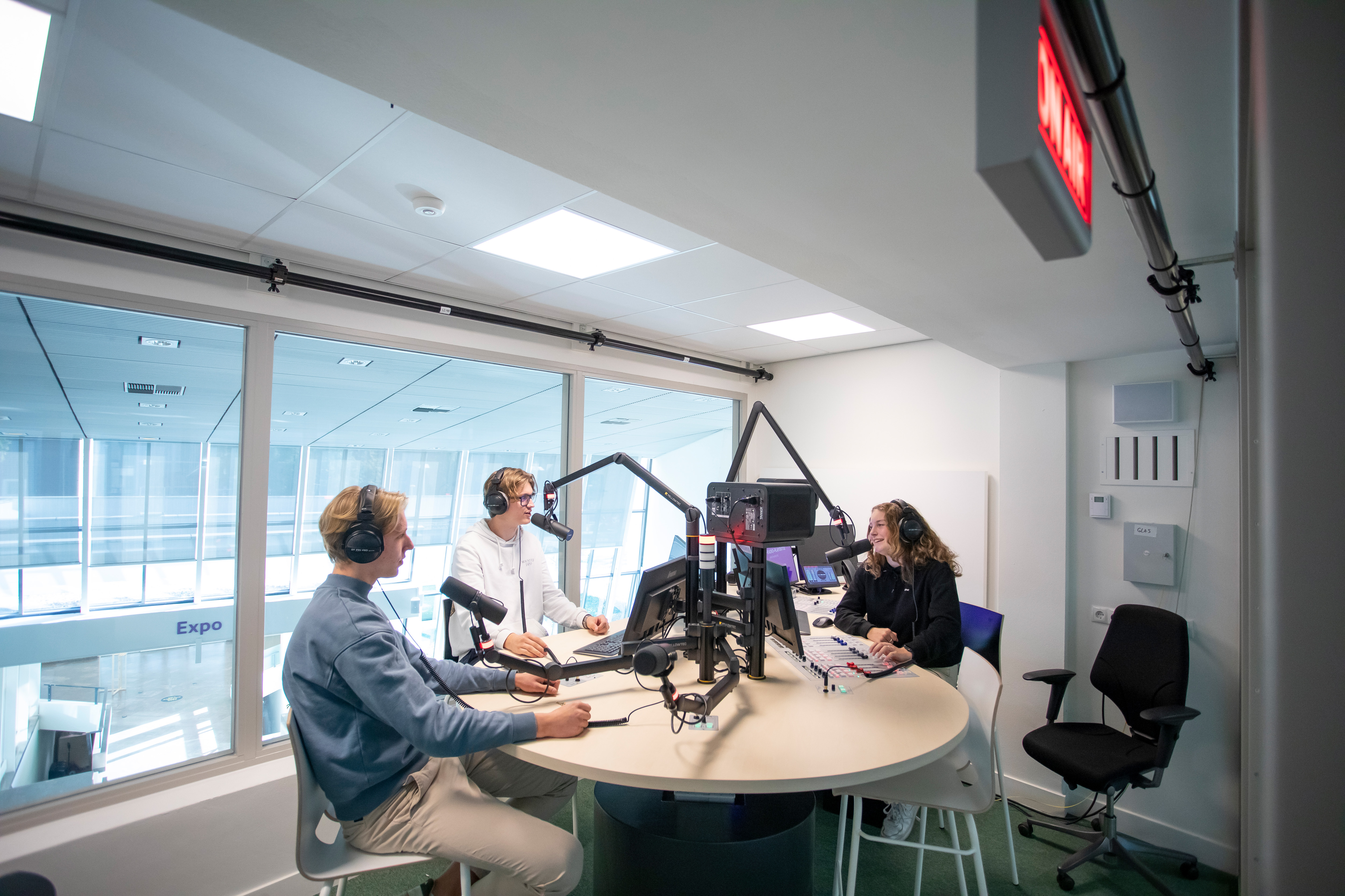 Drie studenten zitten in een radio studio