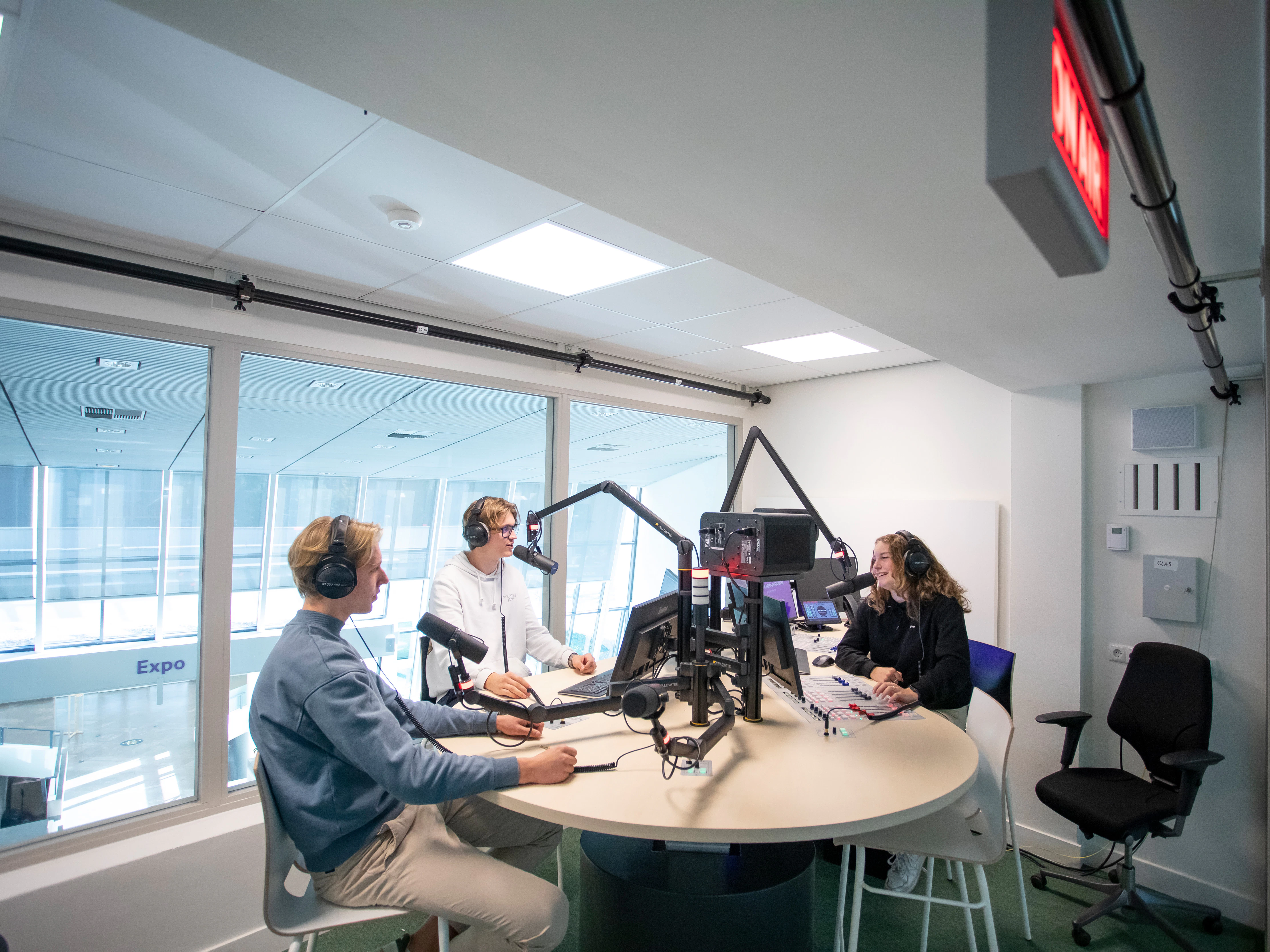 Drie studenten zitten in een radio studio