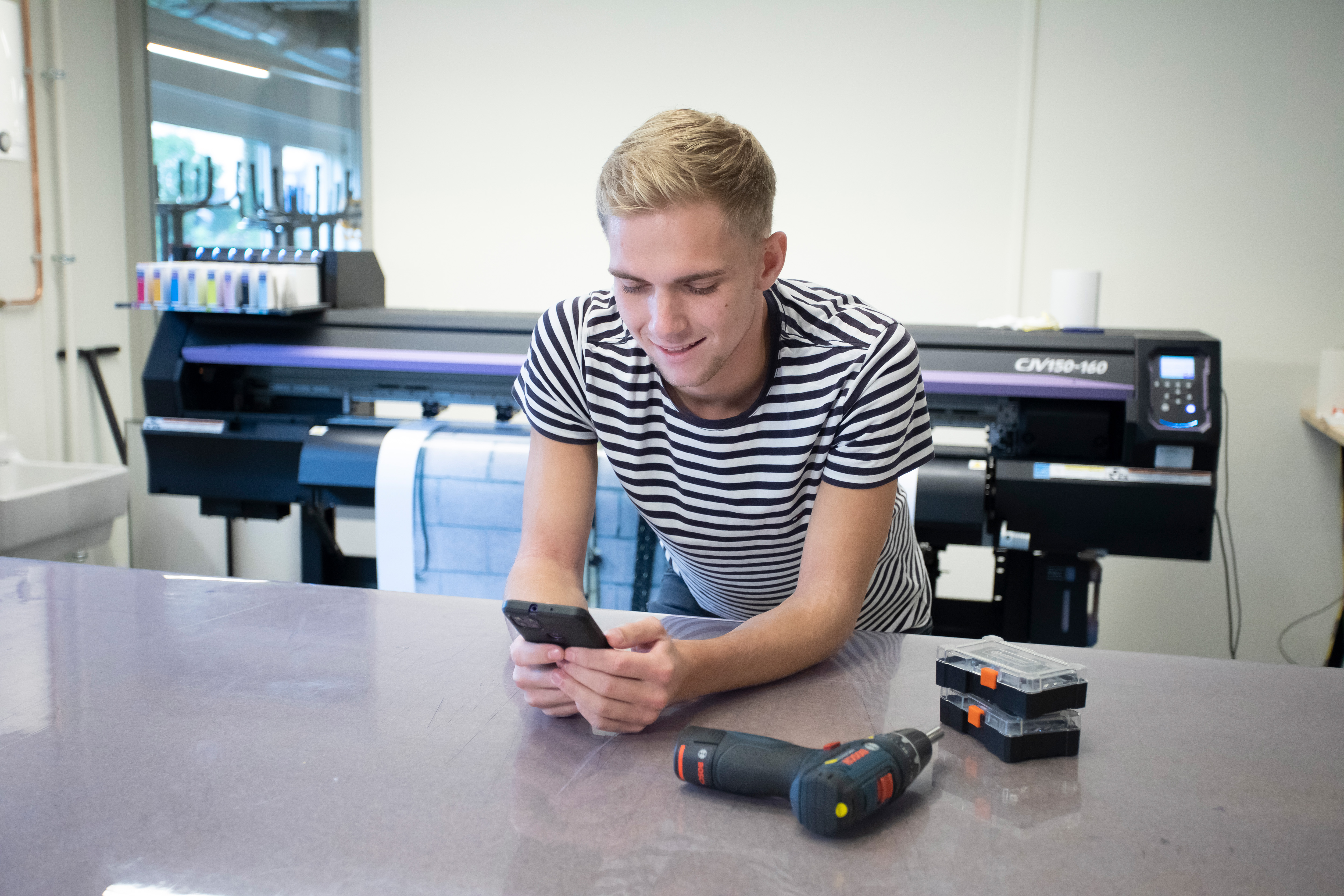 Student leunt op een tafel terwijl hij een telefoon in de hand heeft