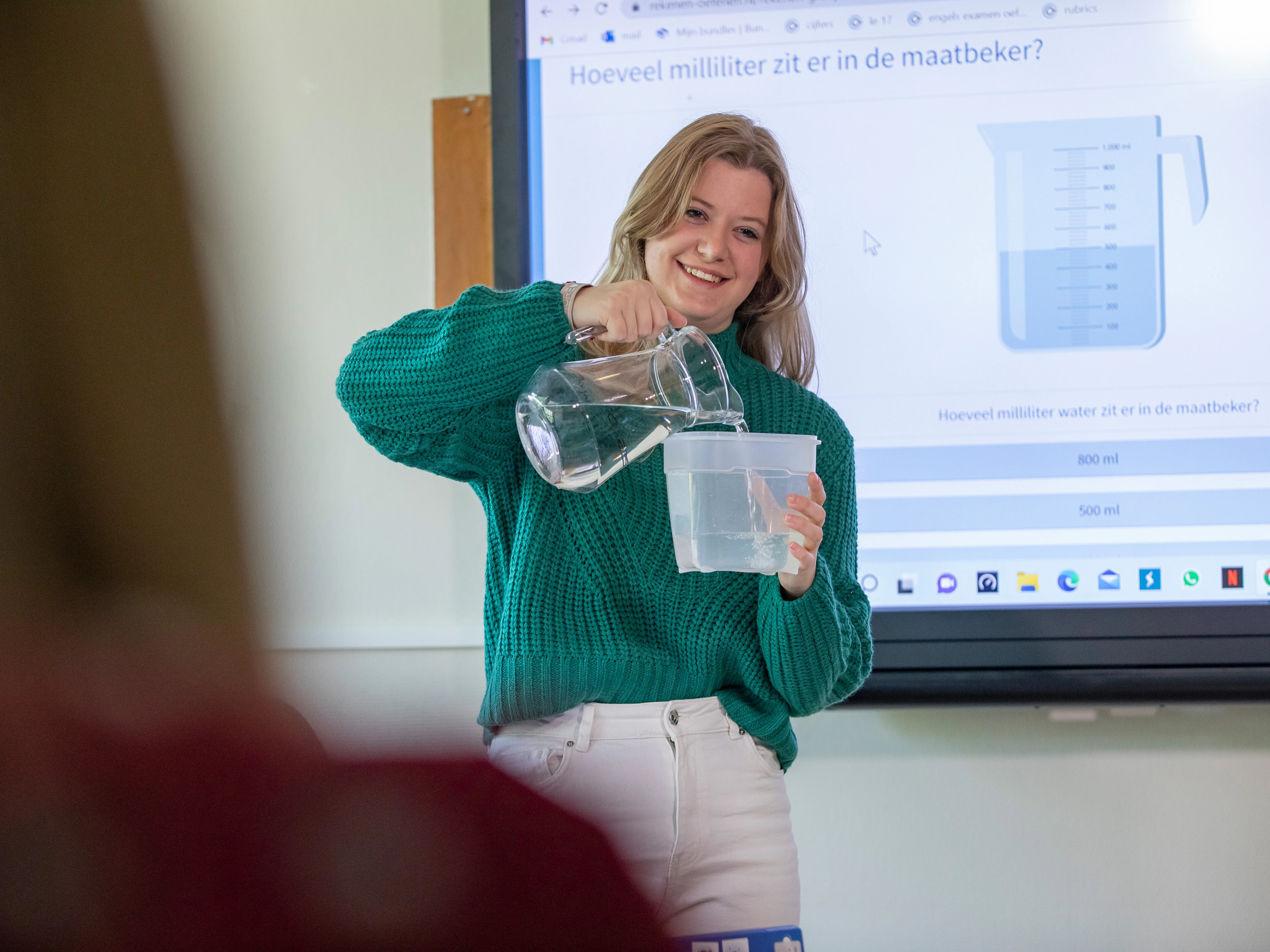 Student staat voor de klas met een maatbeker