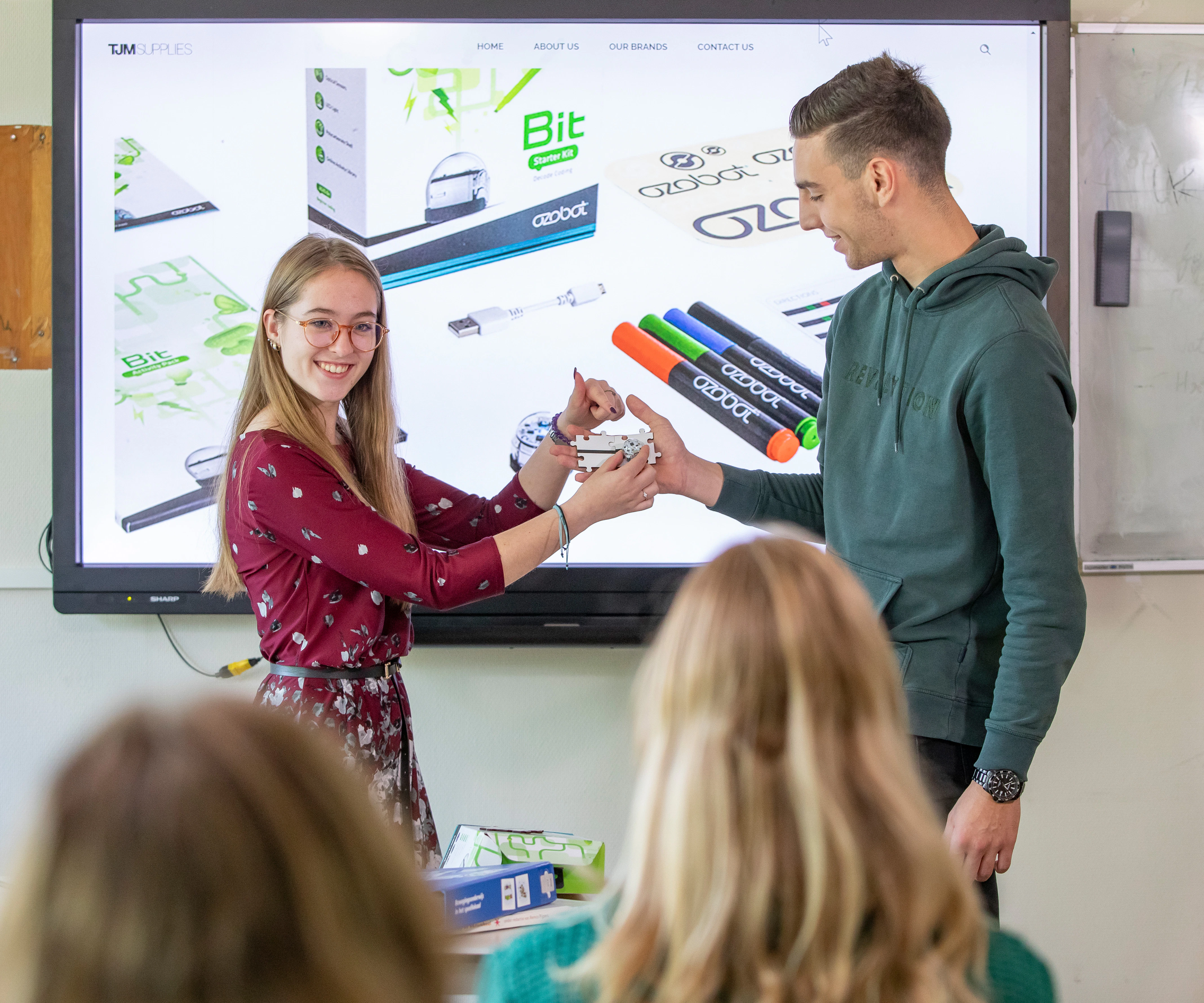 Twee studenten staan voor de klas en leggen iets uit