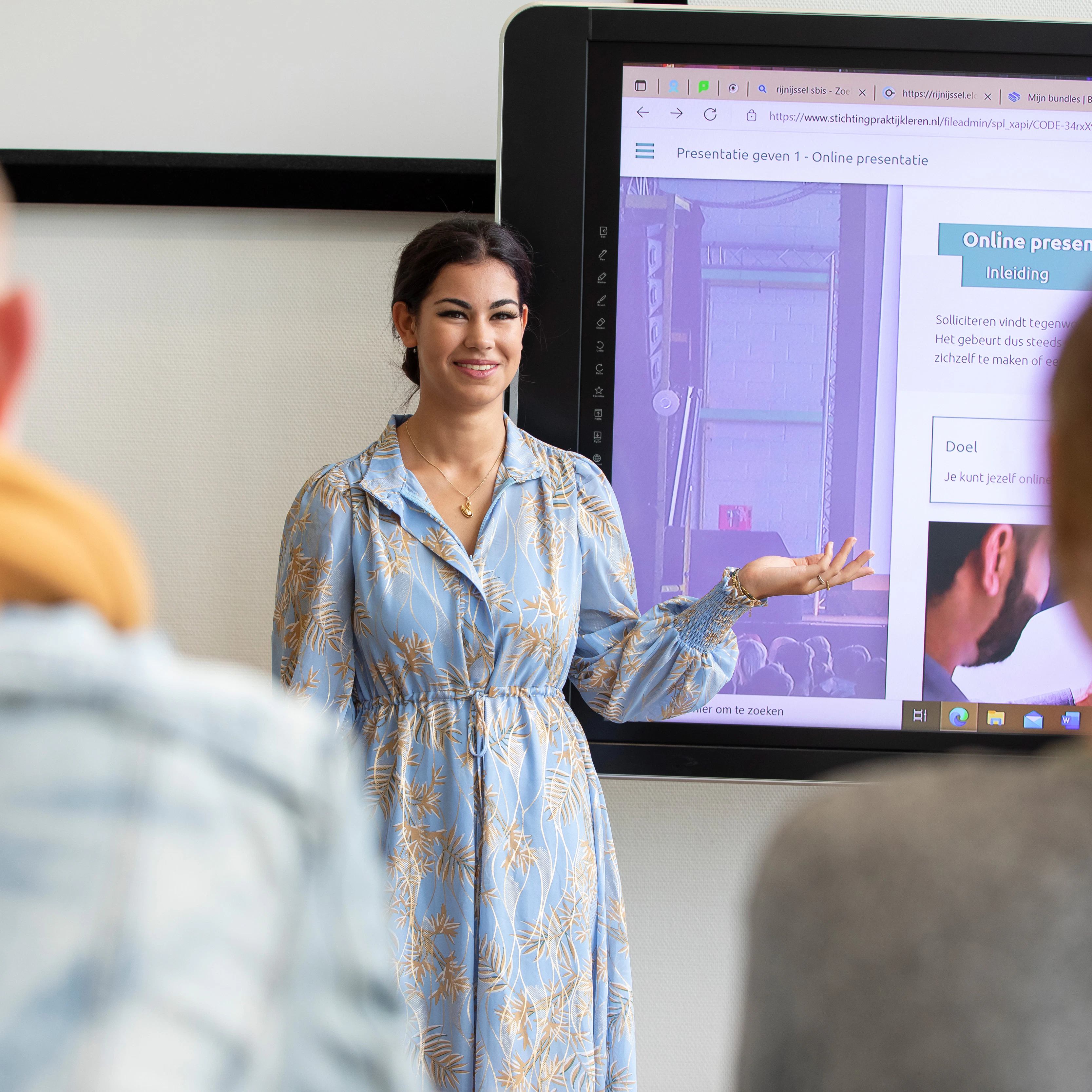 Student staat voor de klas en wijst naar het bord