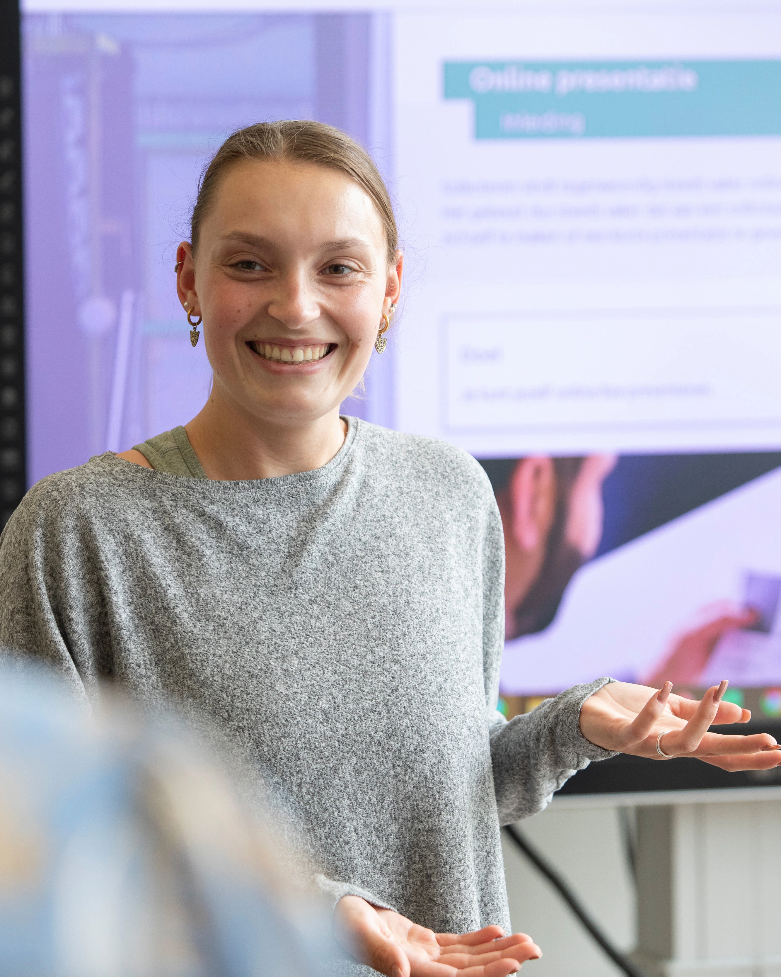 student staat voor de klas en wijst naar het bord