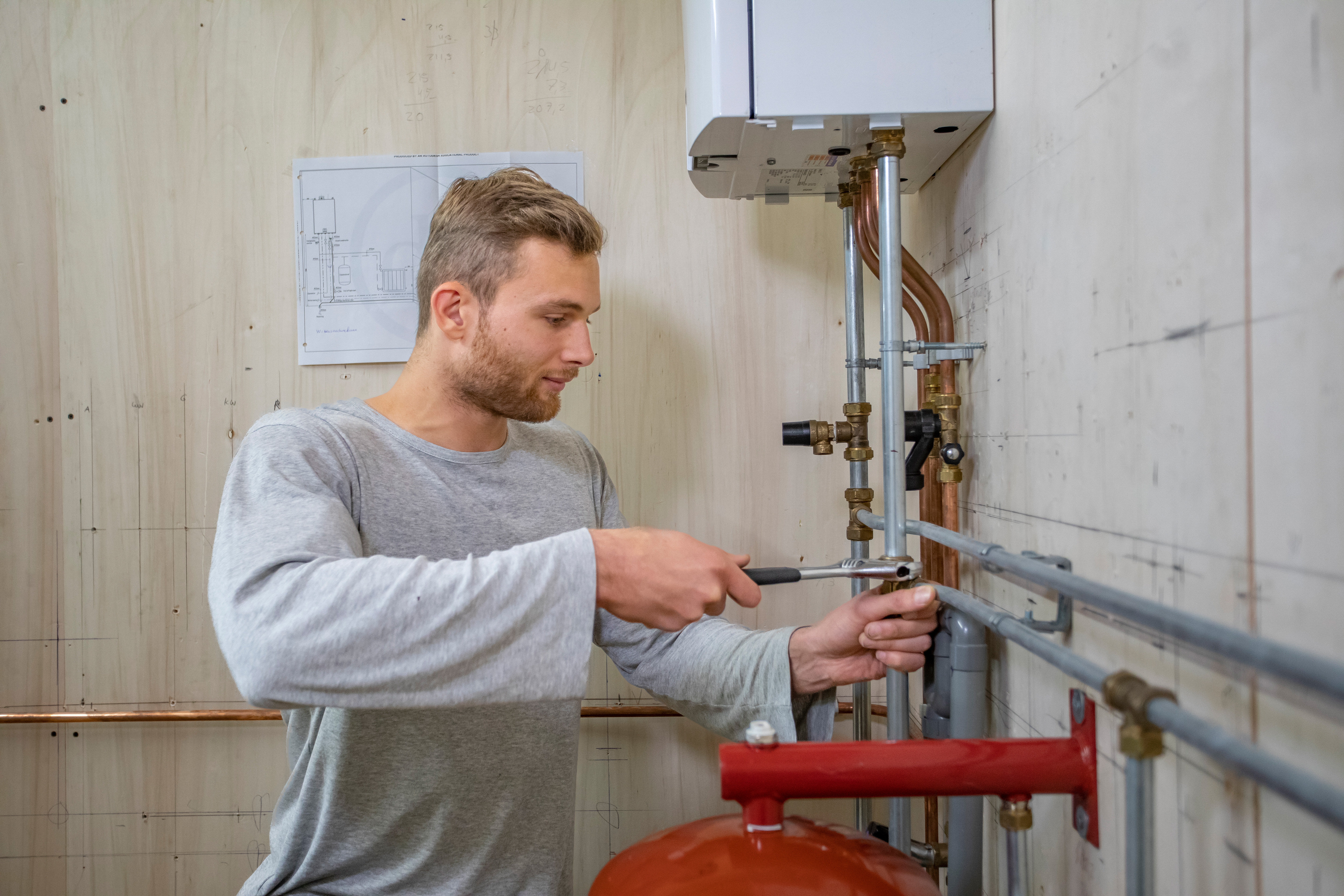 Student draait met een tang aan de buizen van een cv ketel