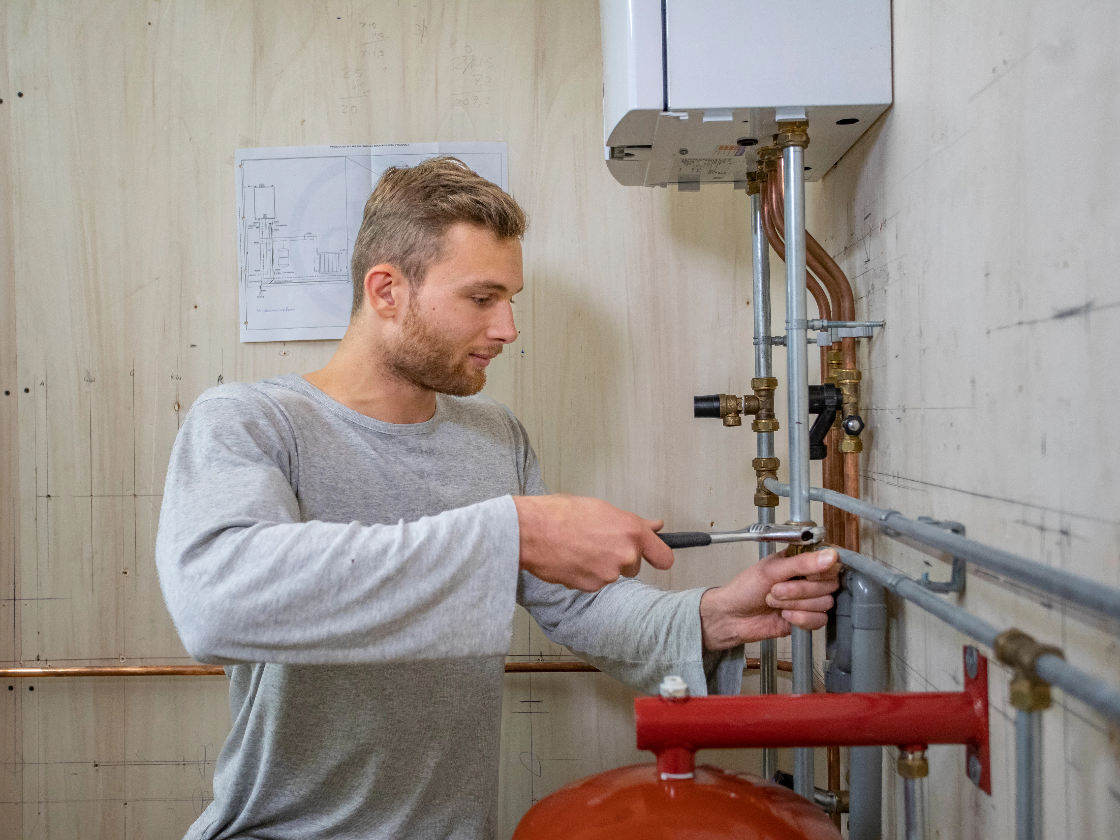 Student draait met een tang aan de buizen van een cv ketel