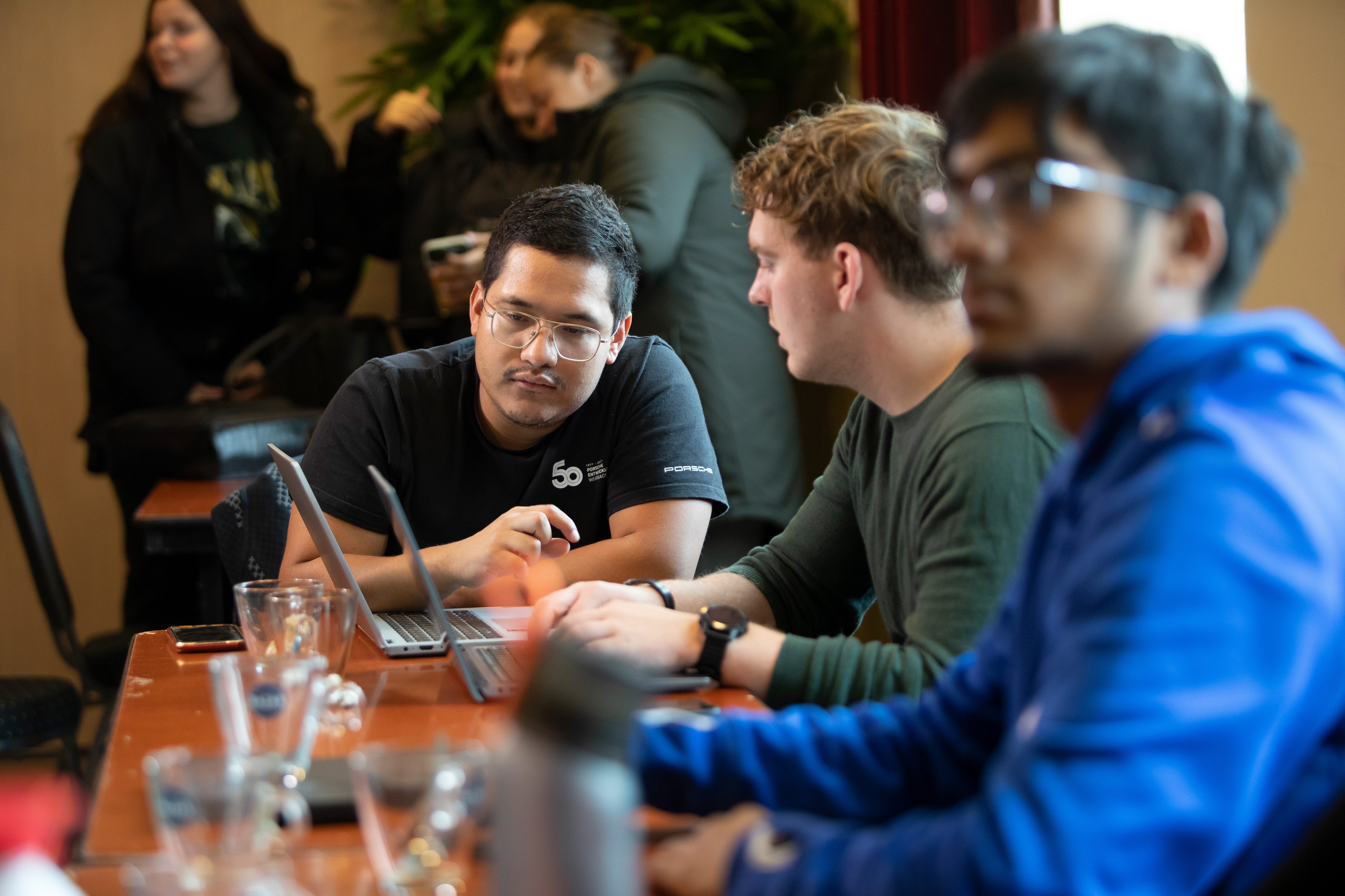 Studenten zitten aan tafel en kijken naar een laptopscherm
