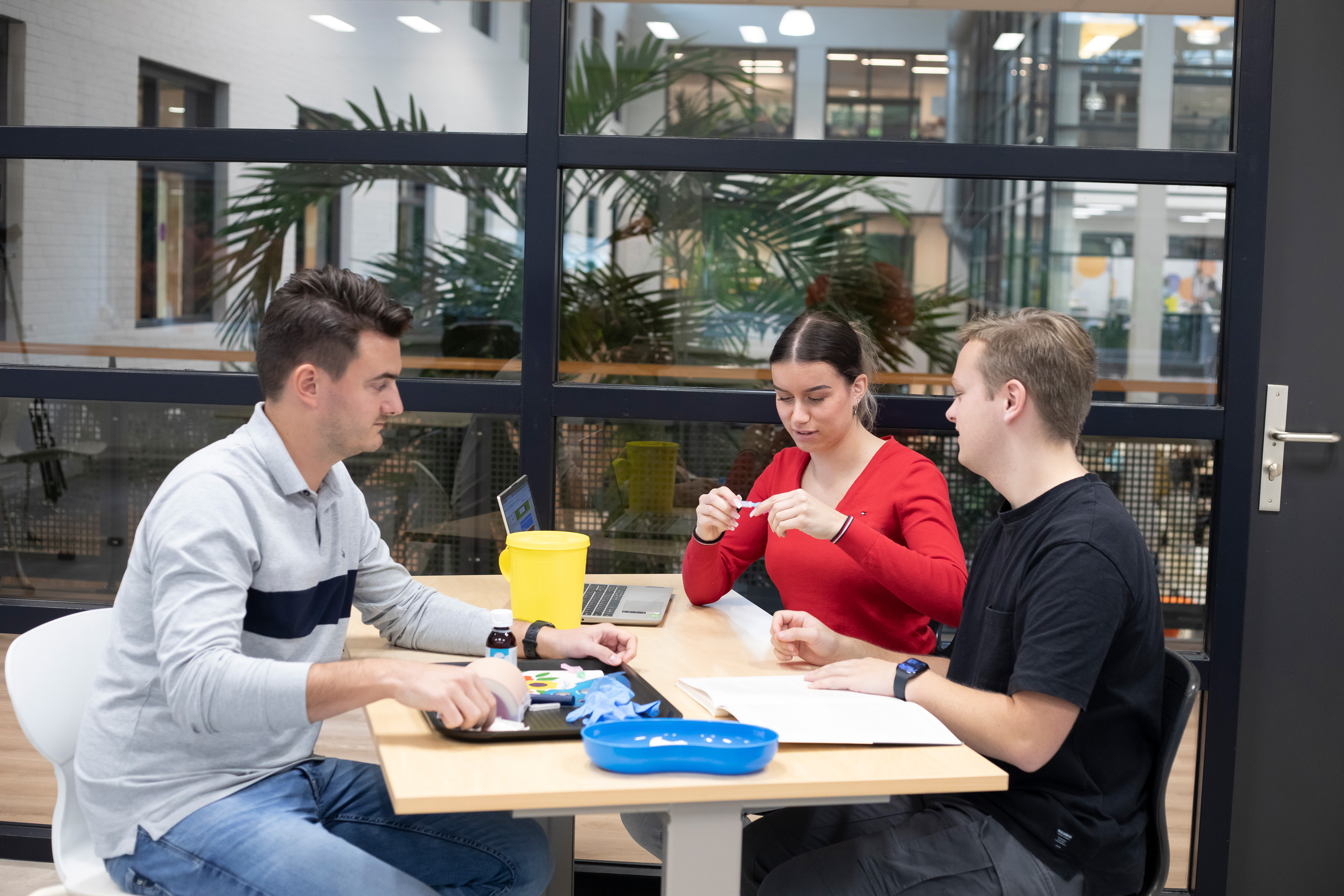 3 studenten zitten aan tafel