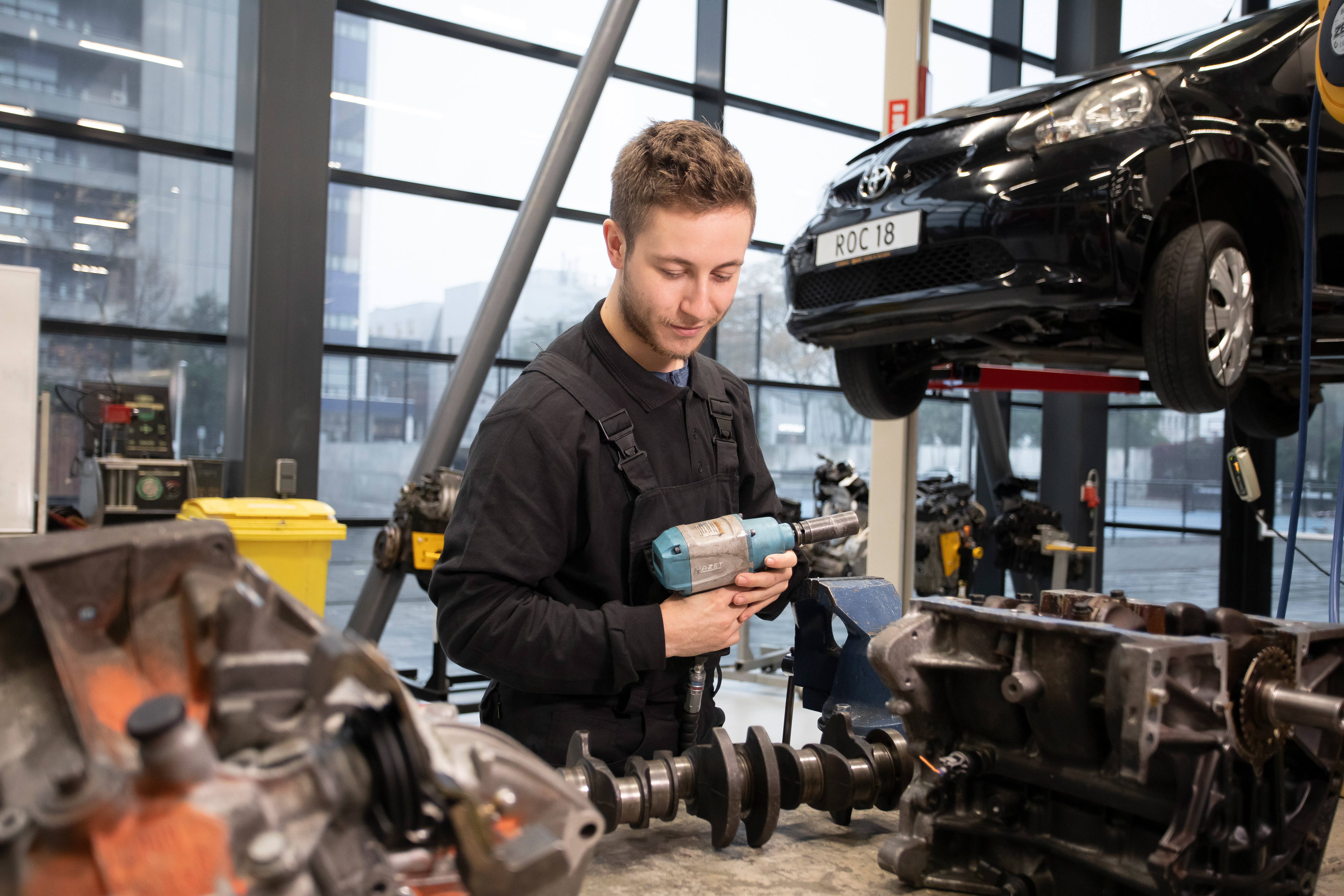 Student houdt een machine vast waarmee hij een wiel van een auto af kan draaien