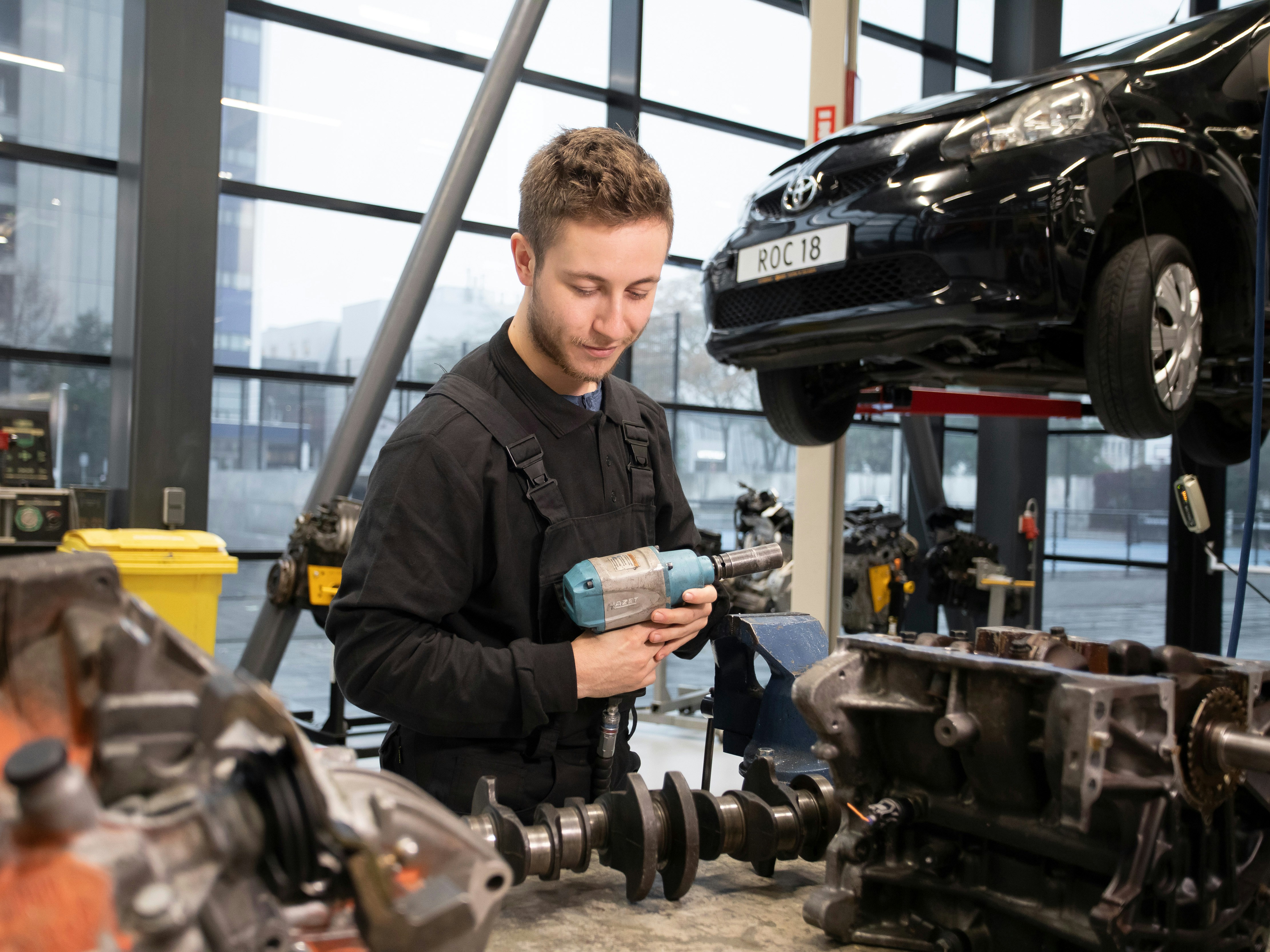 Student houdt een machine vast waarmee hij een wiel van een auto af kan draaien