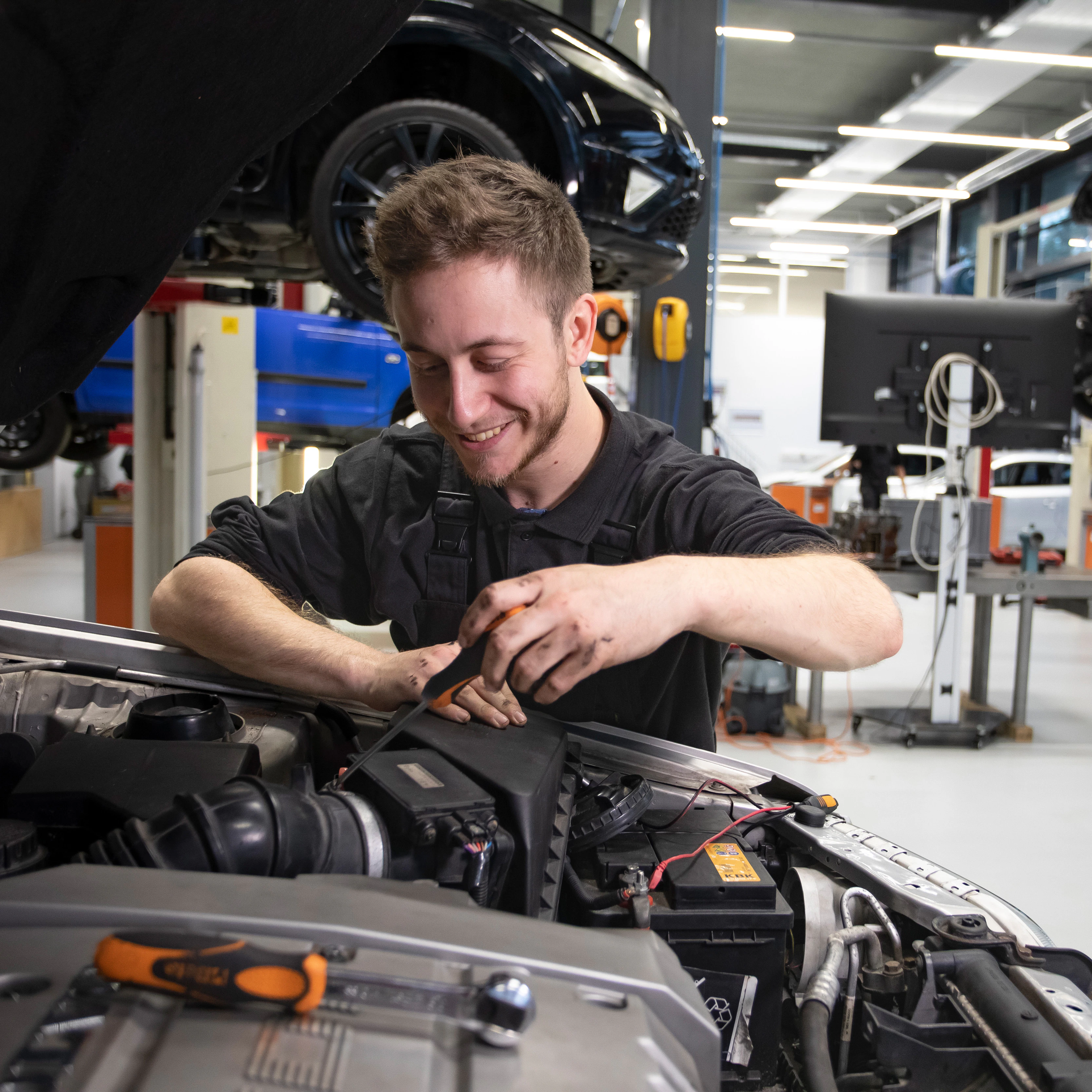Student is bezig onder de motorkap van de auto