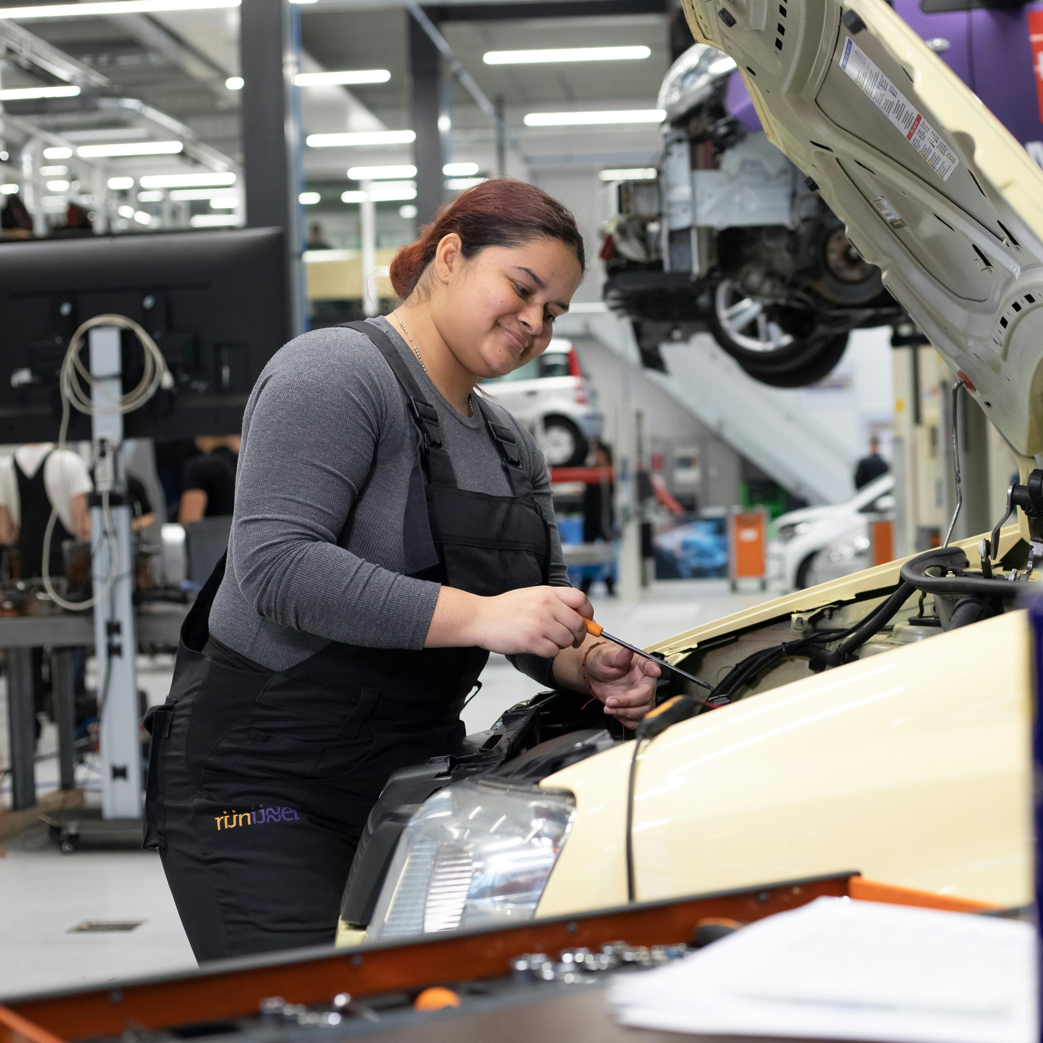Student is bezig onder de motorkap van de auto
