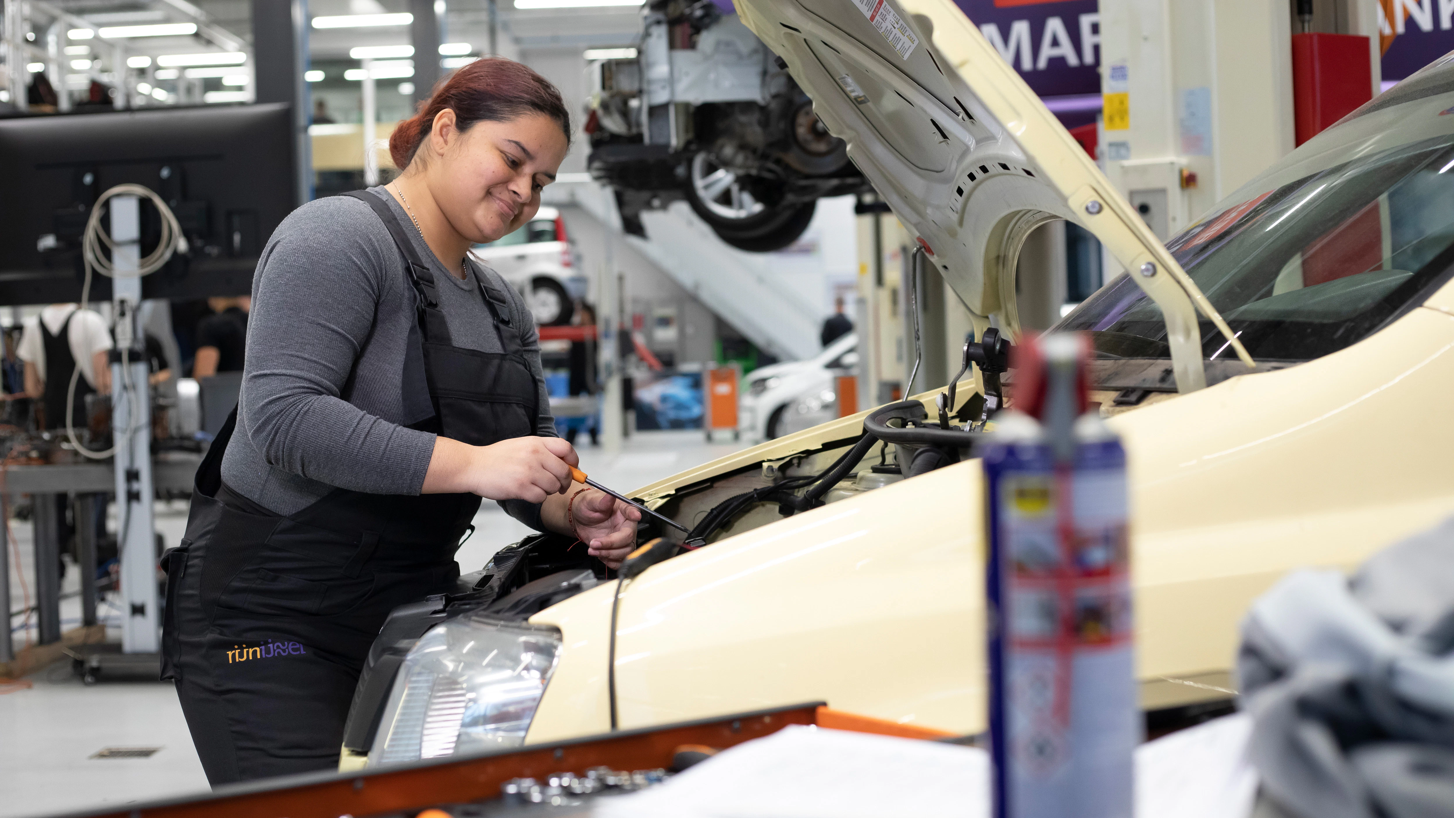 Student is aan het werk onder de motorkap van een auto