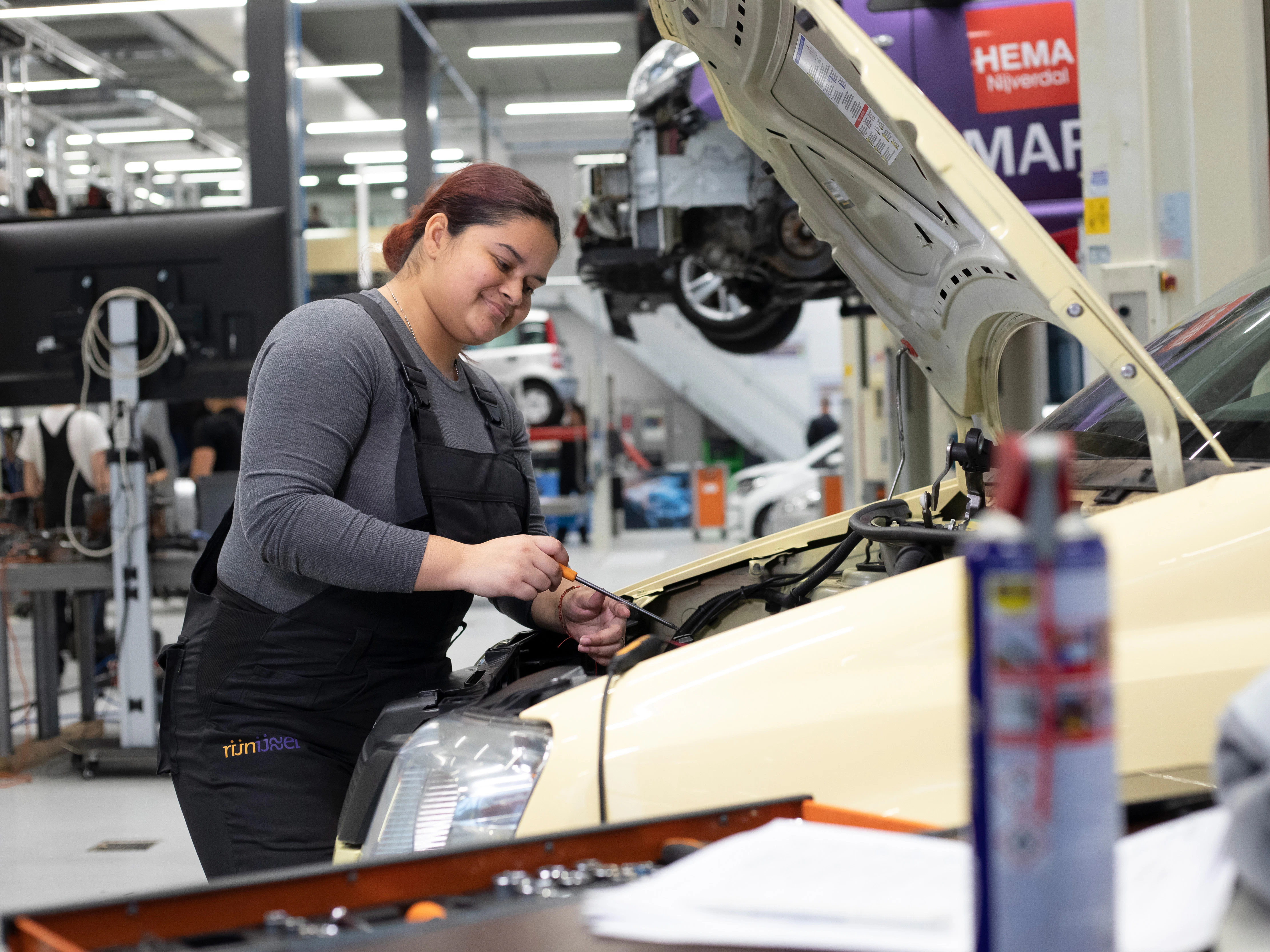 Student is bezig onder de motorkap van de auto