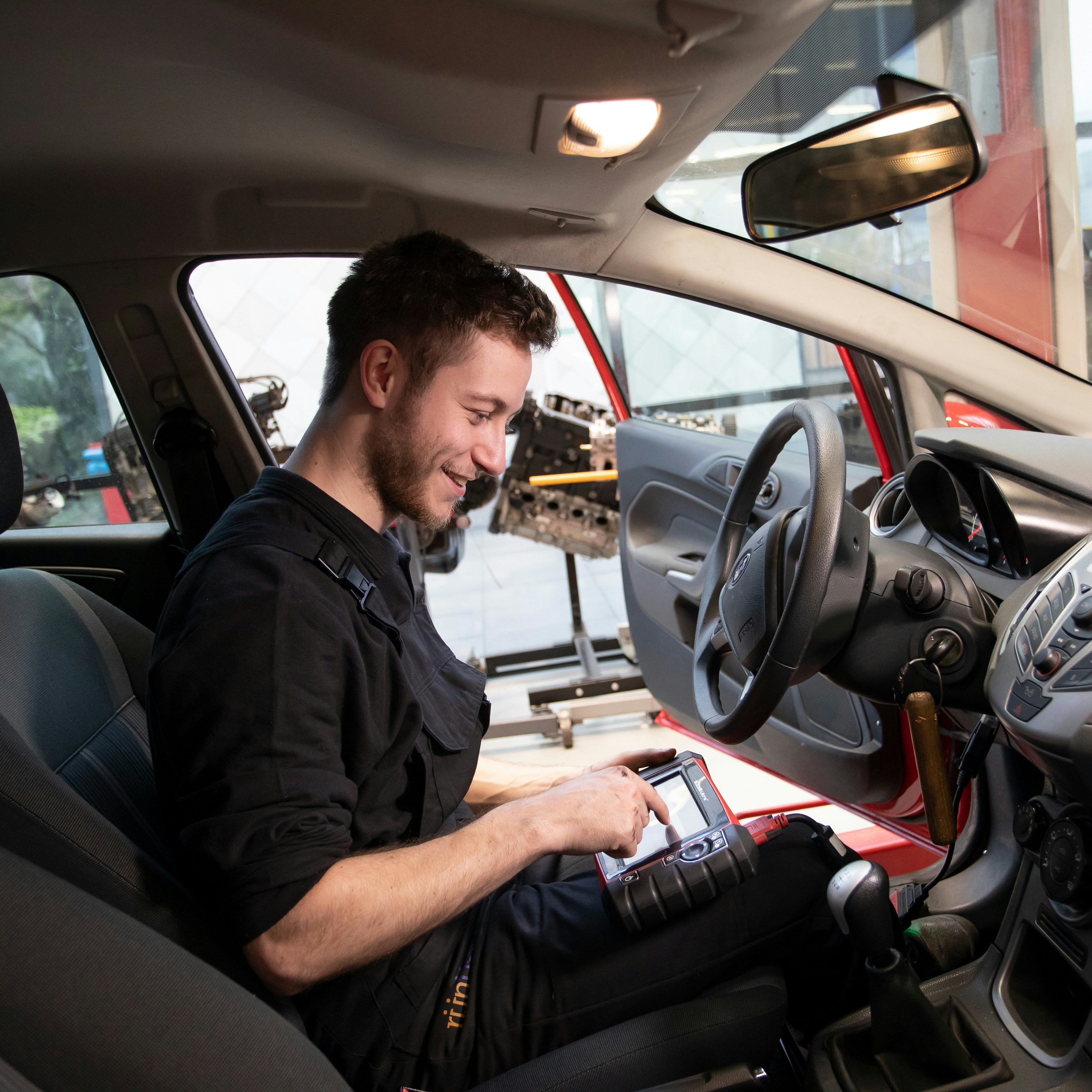 Student zit in een auto en houdt een scherm vast