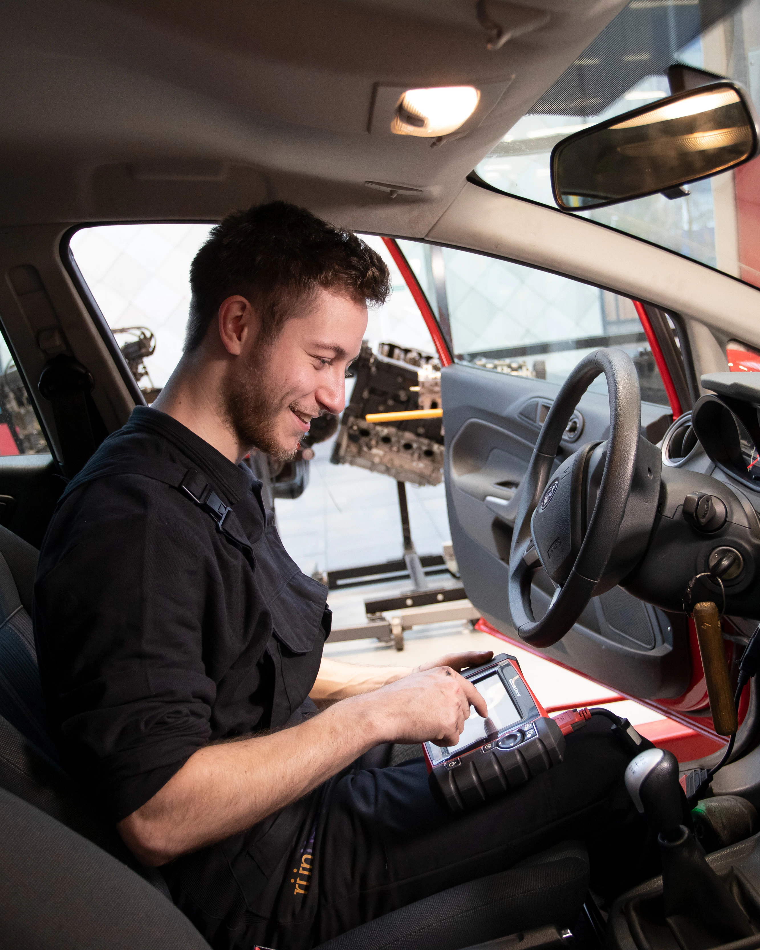 Student zit in de auto en houdt een scherm vast