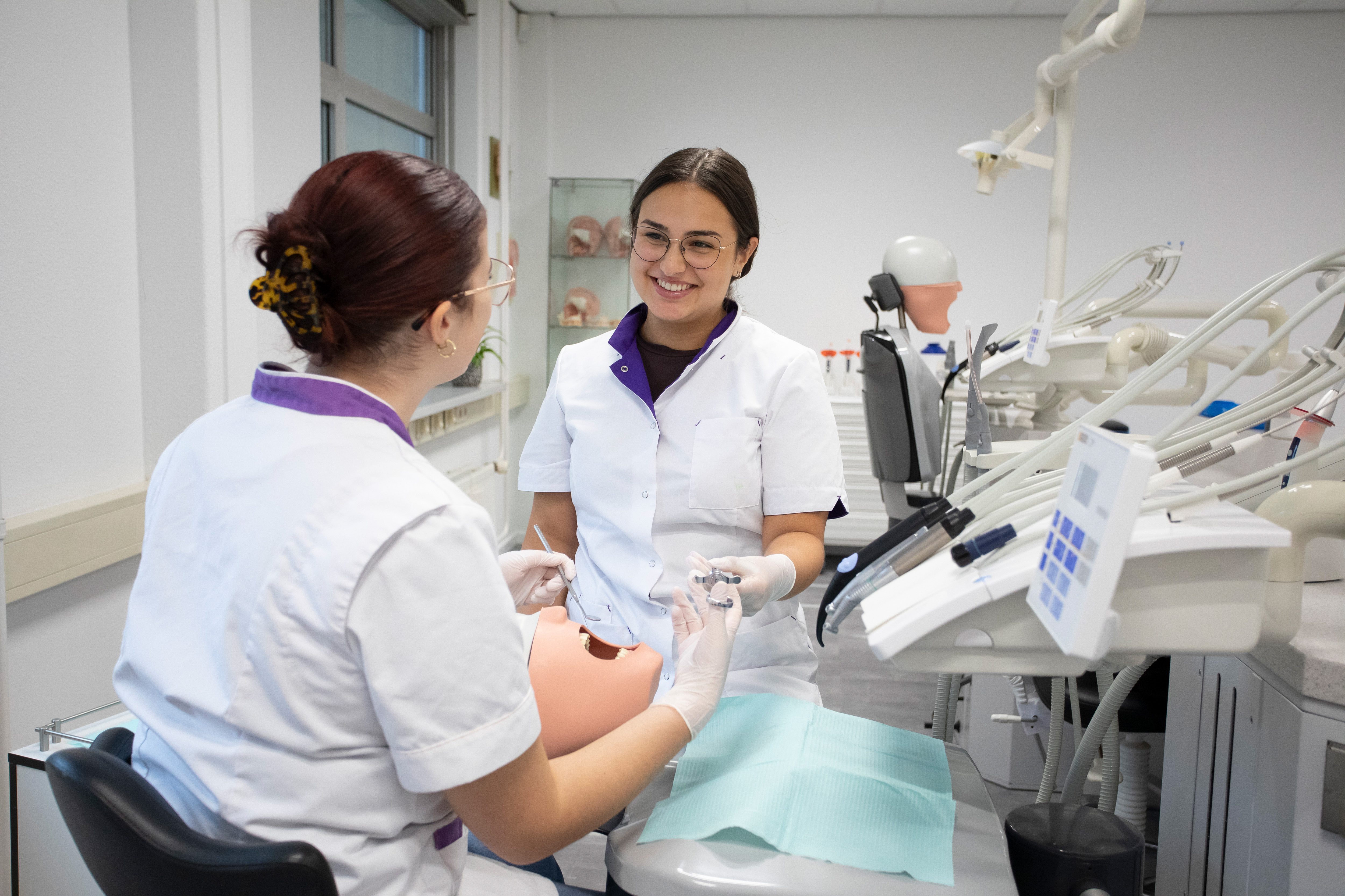 twee studenten zijn in tandartskleding met het gebit van een patiënt bezig