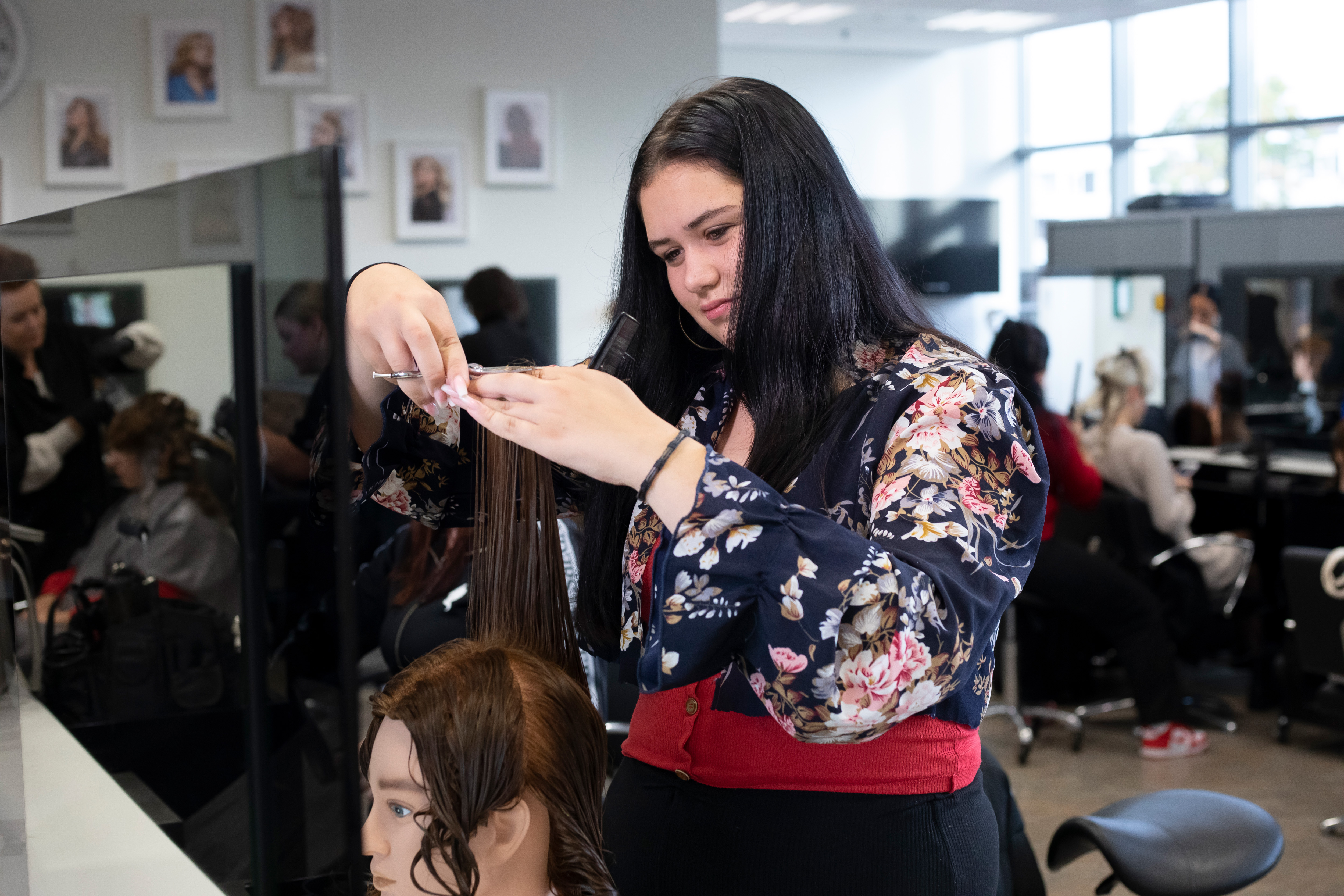 Student knipt het haar van een pop
