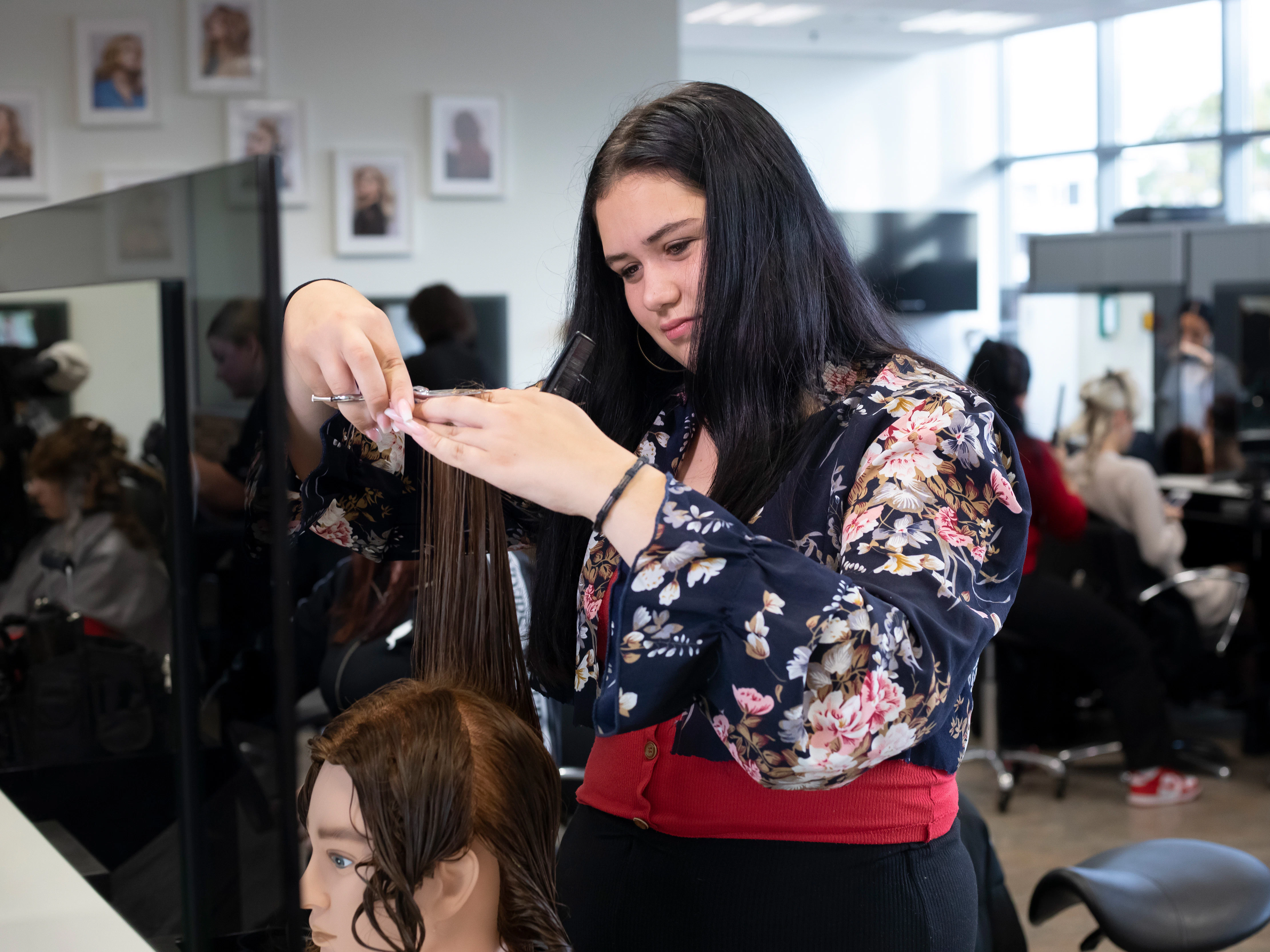 Student knipt het haar van een pop